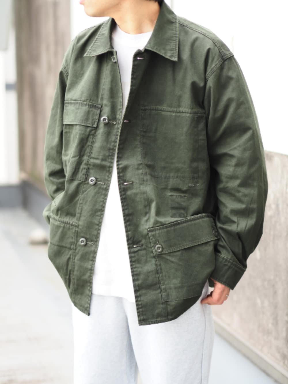 グリーン系のミリタリージャケット、グレー系のスウェットパンツ、ホワイト系のTシャツ/カットソーを着用したメンズの春コーディネートの2枚目の写真