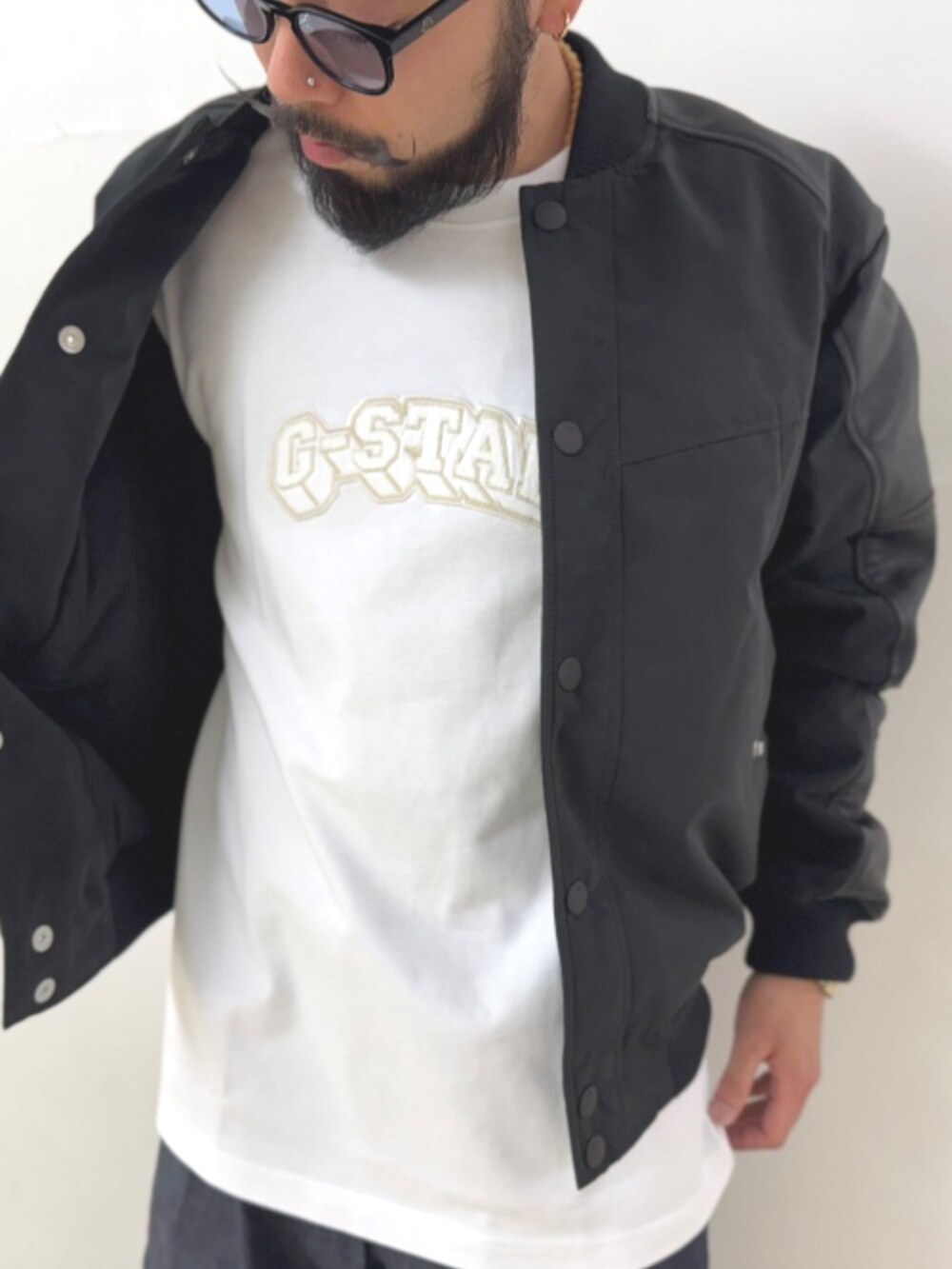 ブラック系のスタジャン、ブルー系のデニムパンツ、ブルー系のキャップを着用したメンズの秋コーディネートの2枚目の写真