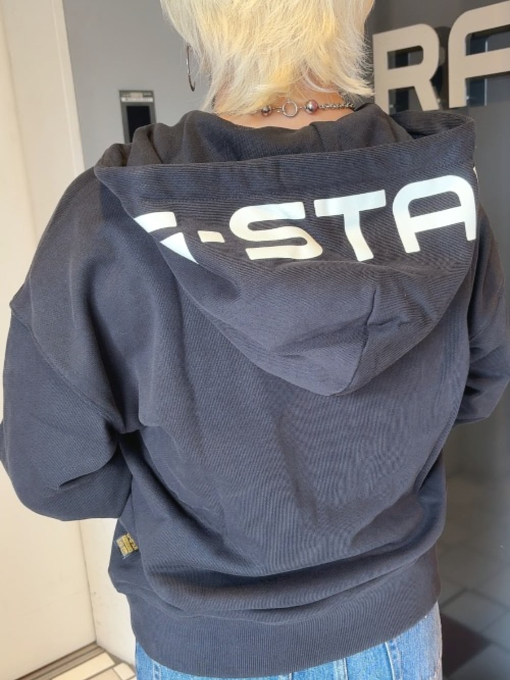 ブラック系のパーカー、ブルー系のデニムスカートを着用したレディースの秋コーディネートの2枚目の写真