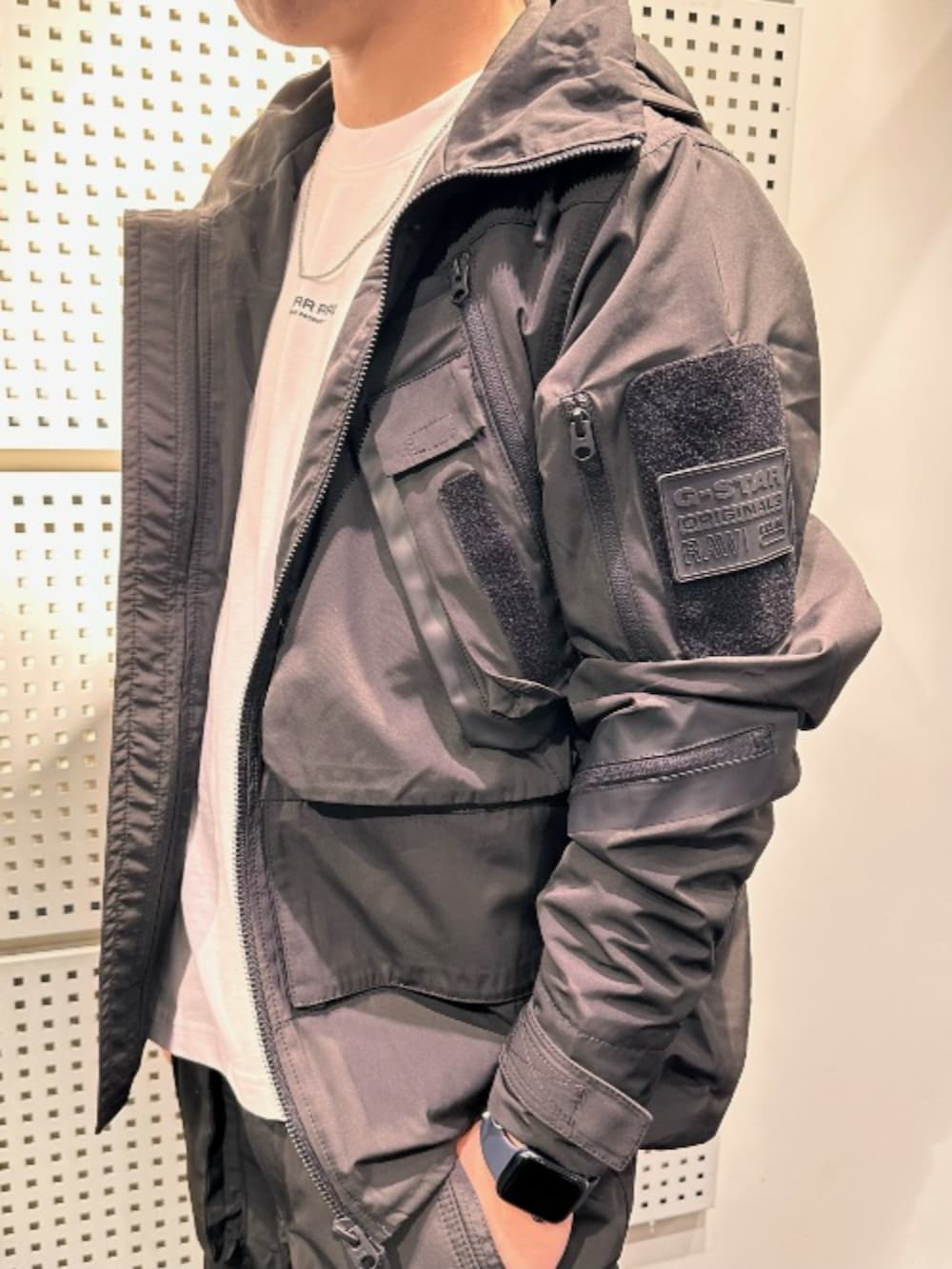 ホワイト系のTシャツ/カットソー、ブラック系のナイロンジャケット、ブラック系のカーゴパンツを着用したメンズの秋コーディネートの2枚目の写真