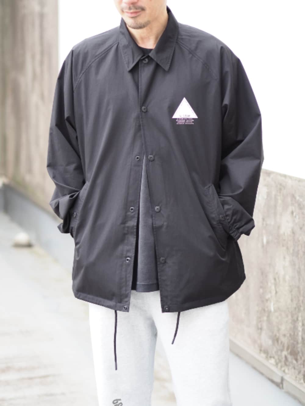 ブラック系のナイロンジャケット、グレー系のスウェットパンツを着用したメンズの春コーディネートの3枚目の写真