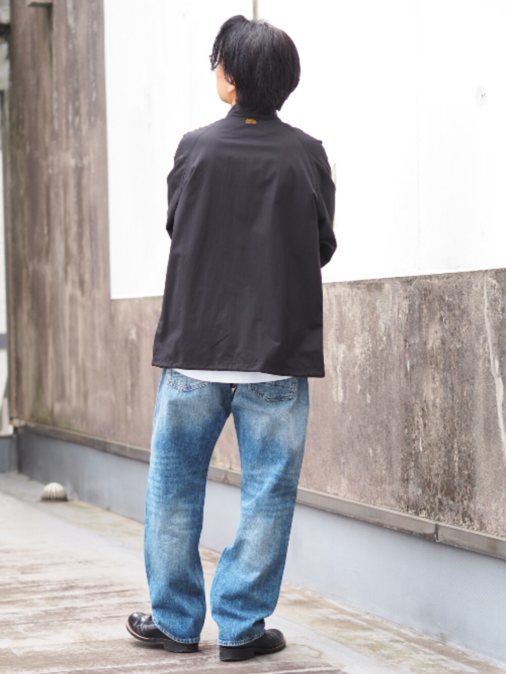 ブラック系のナイロンジャケット、ブルー系のデニムパンツ、ホワイト系のTシャツ/カットソーを着用したメンズの春コーディネートの2枚目の写真