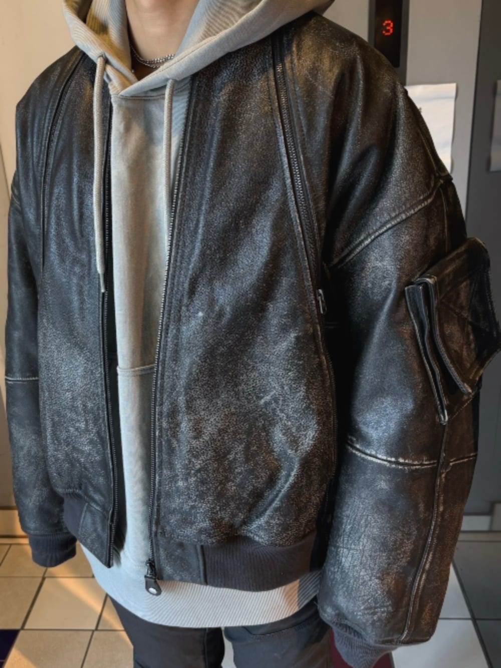 ブラック系のMA-1、ブラック系のデニムパンツ、グレー系のパーカーを着用したメンズの秋コーディネートの2枚目の写真