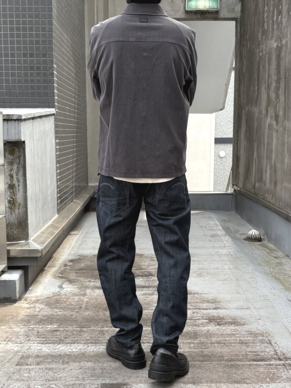 ブラック系のローファー、ホワイト系のTシャツ/カットソー、ブルー系のデニムパンツを着用したメンズの秋コーディネートの3枚目の写真
