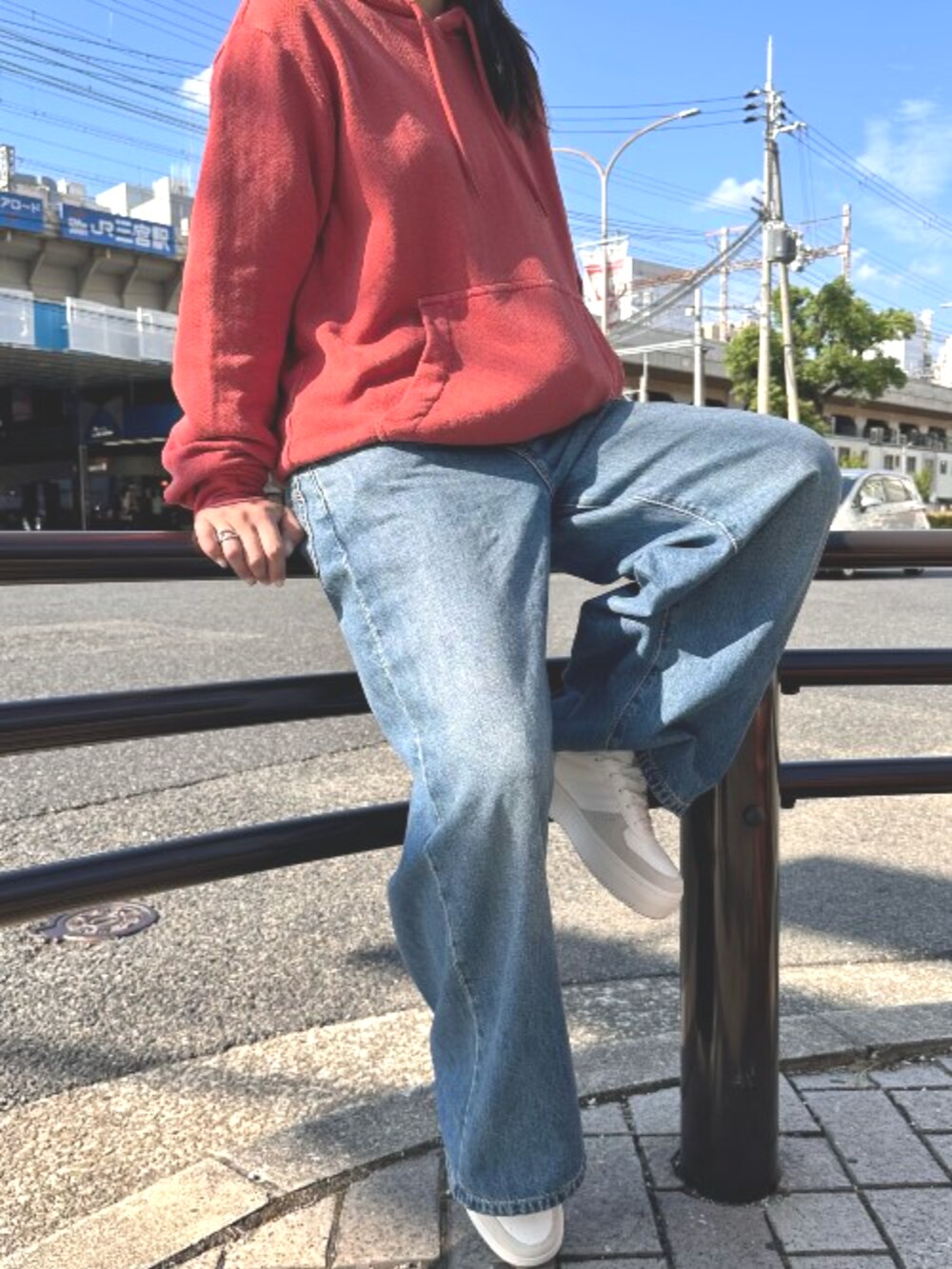 レッド系のパーカー、ブルー系のデニムパンツを着用したレディースの秋コーディネートの2枚目の写真