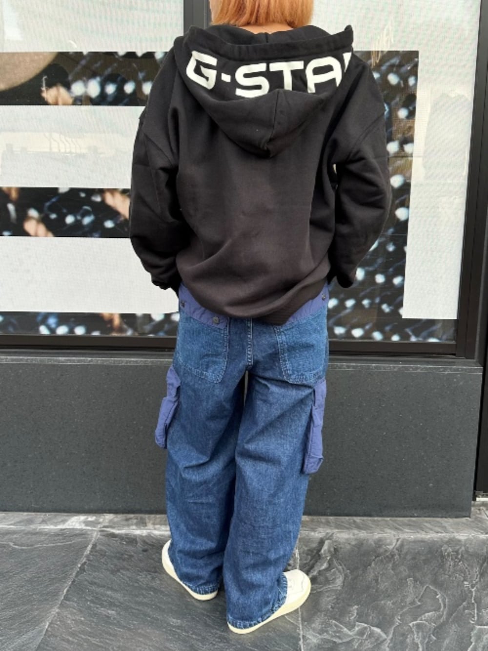 ブルー系のデニムパンツ、ブラック系のパーカーを着用したレディースの秋コーディネートの2枚目の写真