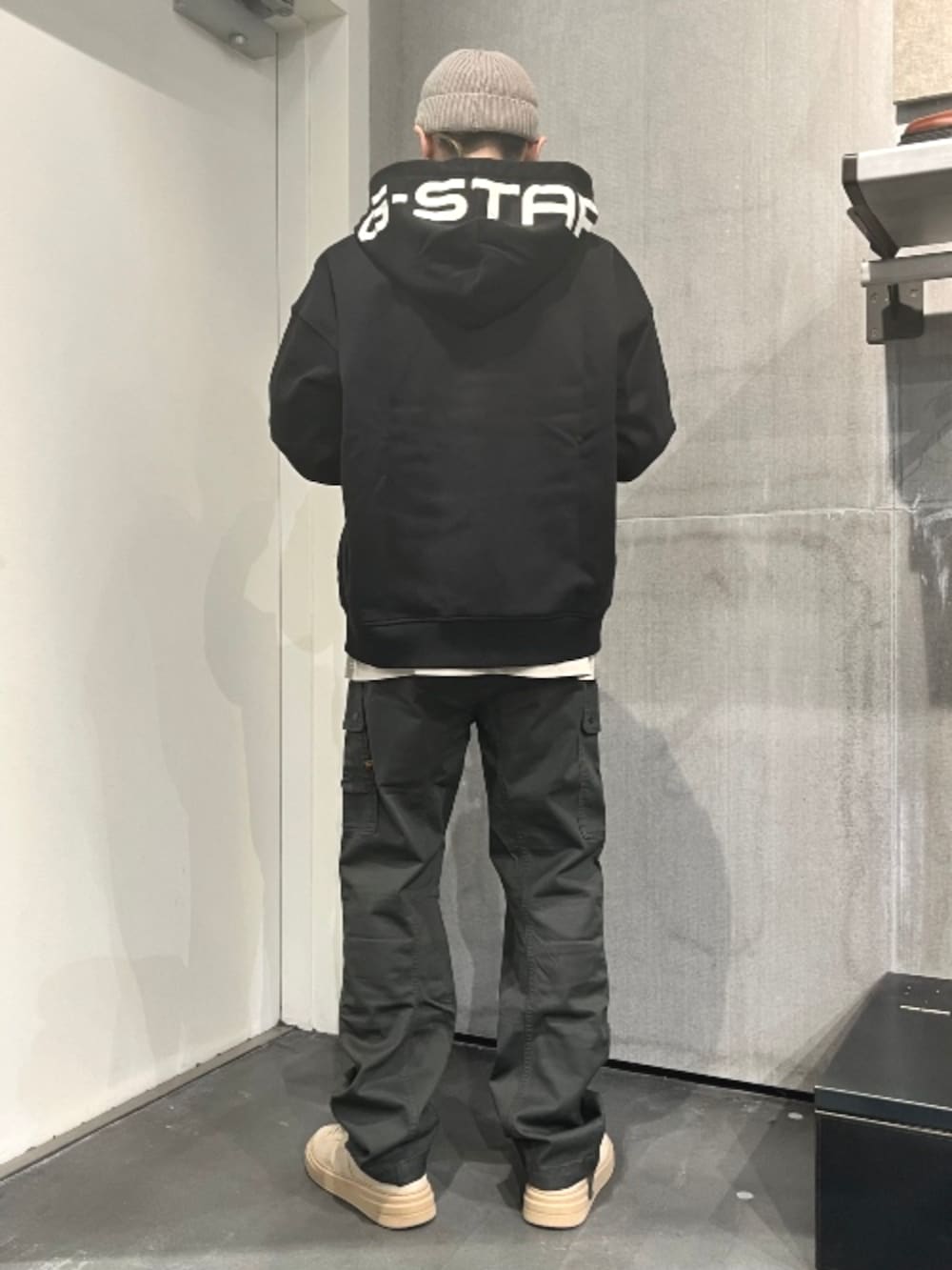 グリーン系のカーゴパンツ、ブラック系のパーカーを着用したメンズの秋コーディネートの2枚目の写真