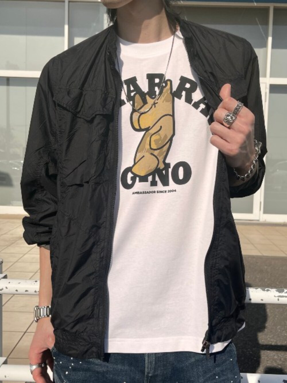 ホワイト系のTシャツ/カットソー、ブラック系のミリタリージャケット、ブルー系のデニムパンツを着用したメンズの春コーディネートの2枚目の写真