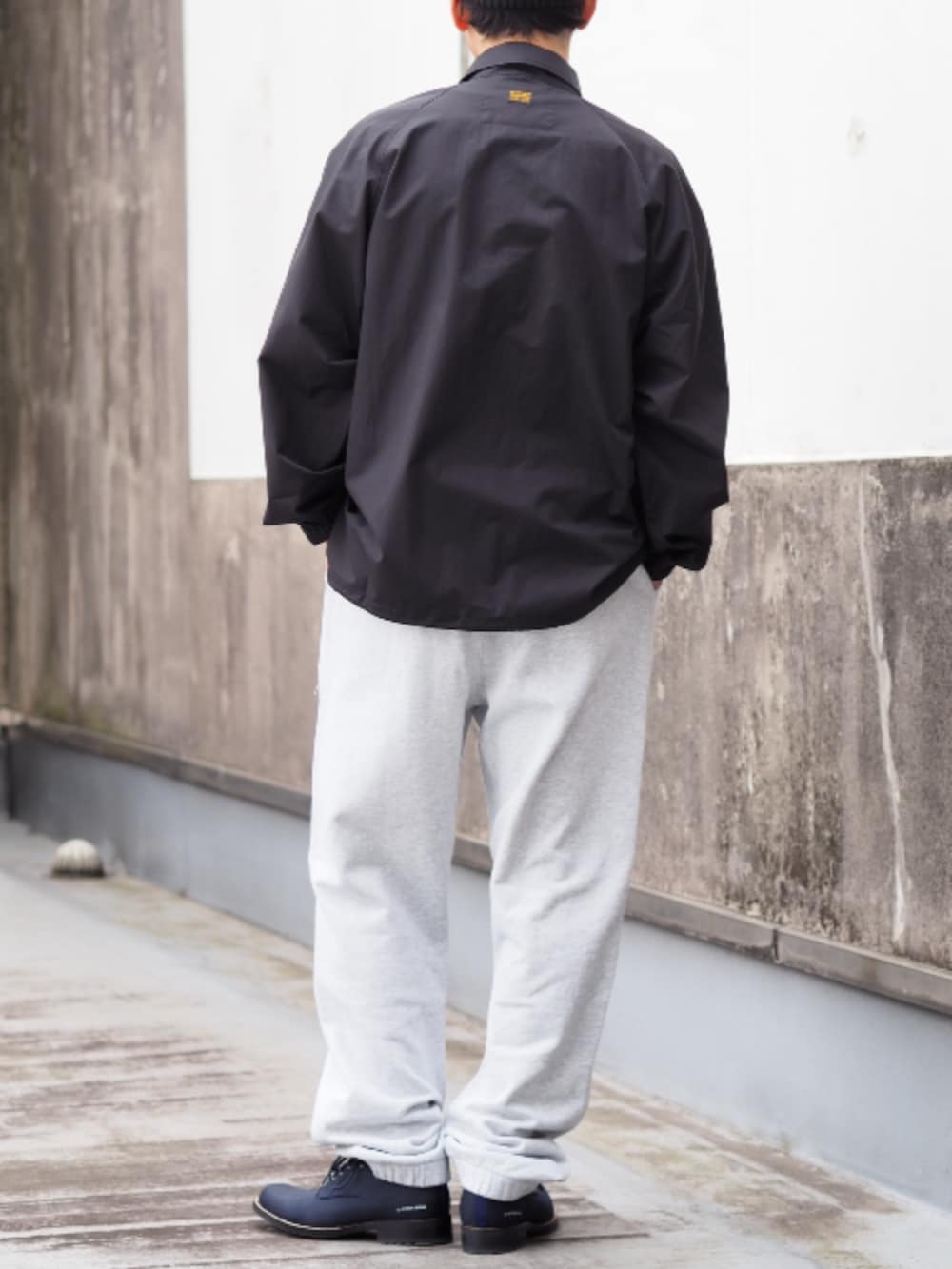 ブラック系のナイロンジャケット、グレー系のスウェットパンツを着用したメンズの春コーディネートの2枚目の写真