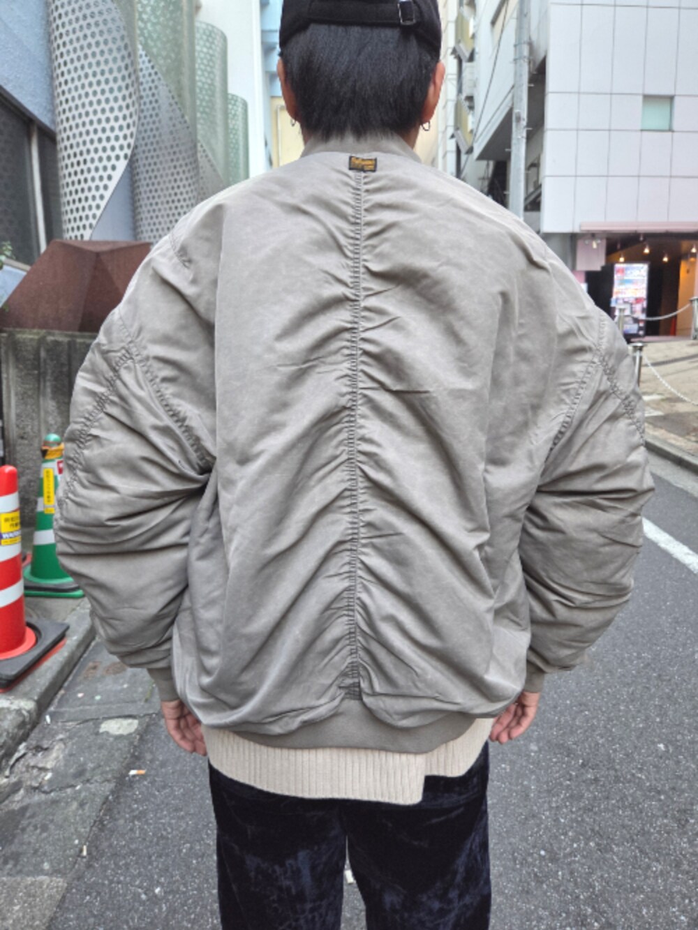ベージュ系のMA-1、ベージュ系のニット/セーター、ブルー系のデニムパンツを着用したメンズの秋コーディネートの3枚目の写真