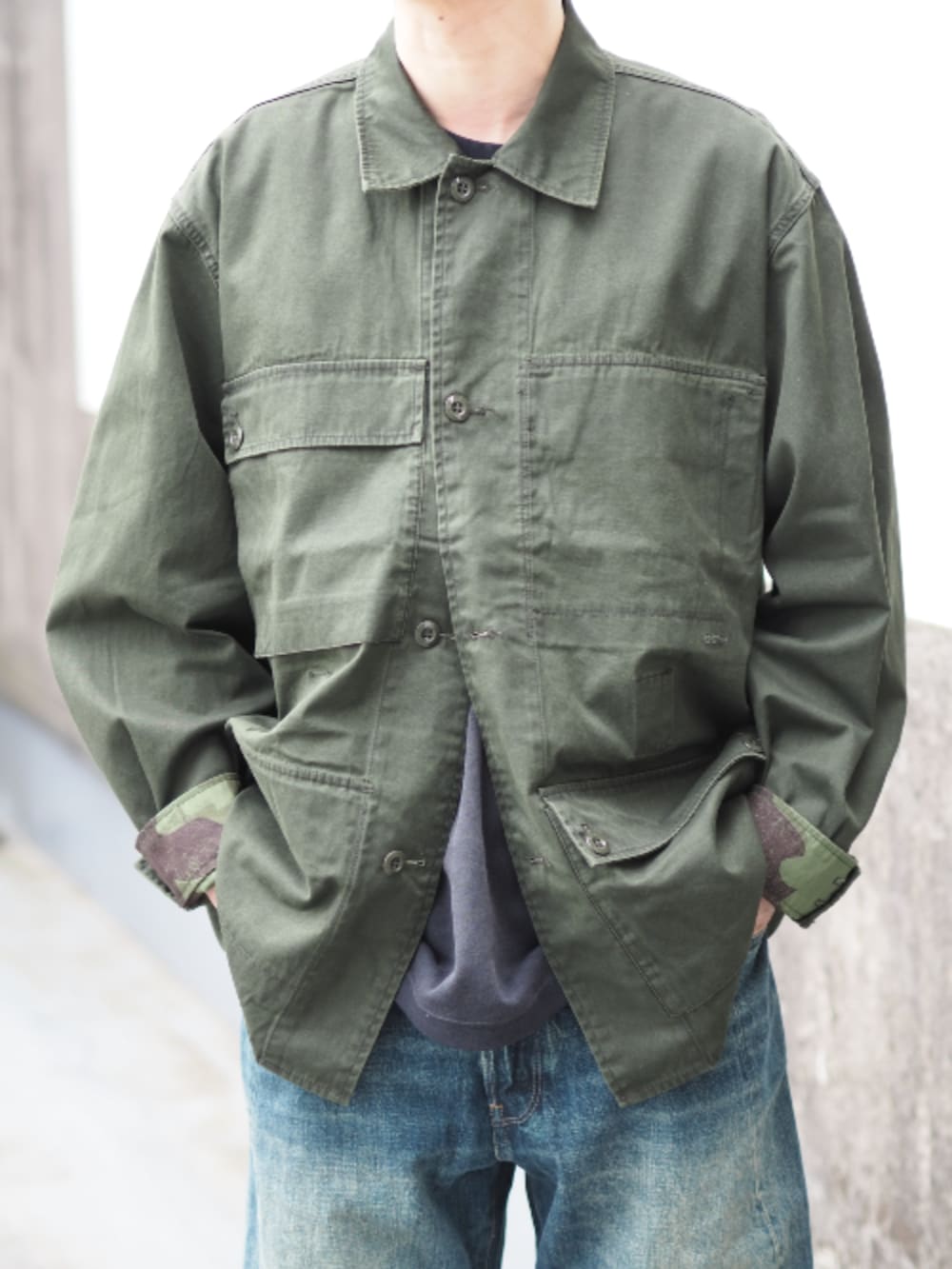 グリーン系のミリタリージャケット、ブルー系のデニムパンツを着用したメンズの春コーディネートの5枚目の写真