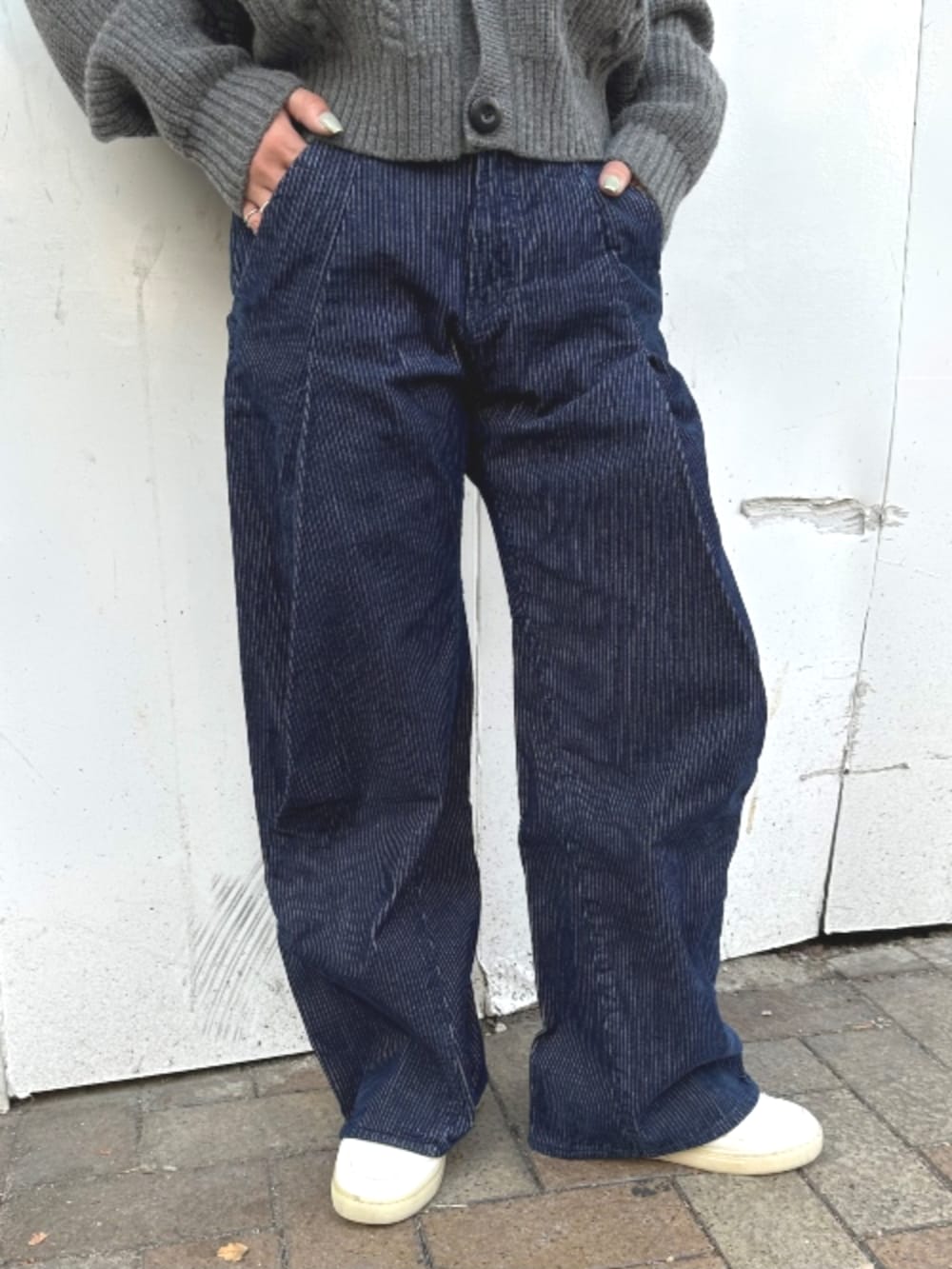 グレー系のカーディガン/ボレロ、ホワイト系のTシャツ/カットソー、ブルー系のデニムパンツを着用したレディースの秋コーディネートの2枚目の写真