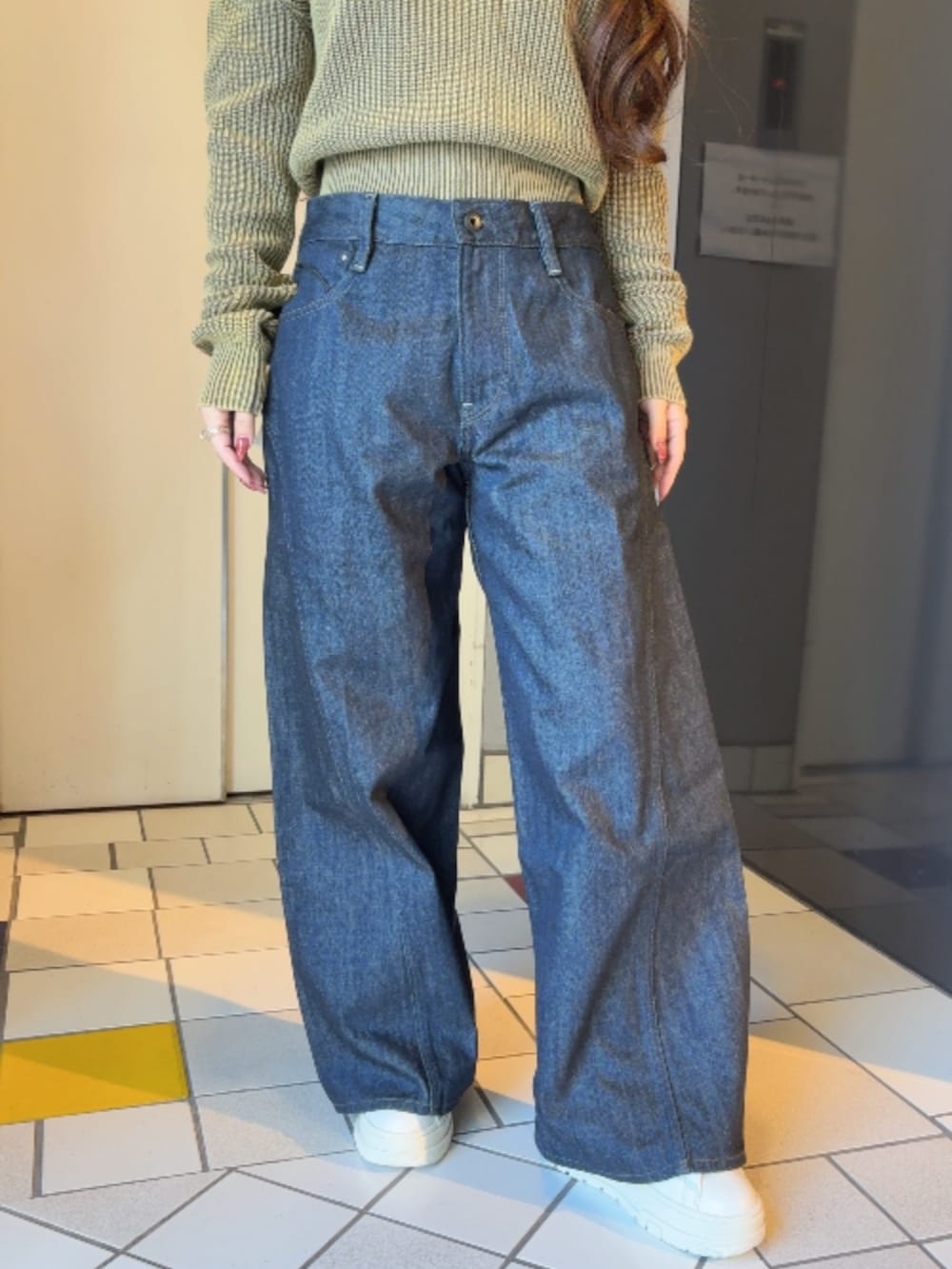 ブラウン系のニット/セーター、ブルー系のデニムパンツを着用したレディースの冬コーディネートの2枚目の写真