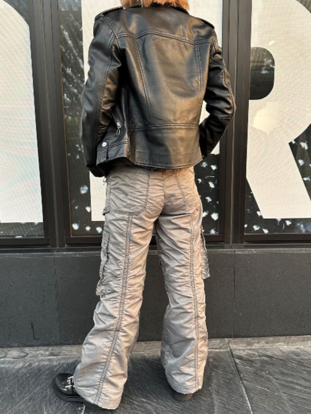 ブラック系のライダースジャケット、ブラック系のTシャツ/カットソー、グレー系のカーゴパンツを着用したレディースの秋コーディネートの3枚目の写真