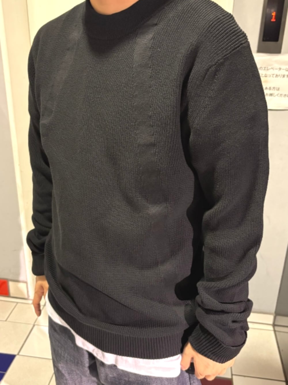 ブラック系のスタジャン、ブラック系のニット/セーター、ブルー系のデニムパンツを着用したメンズの秋コーディネートの3枚目の写真