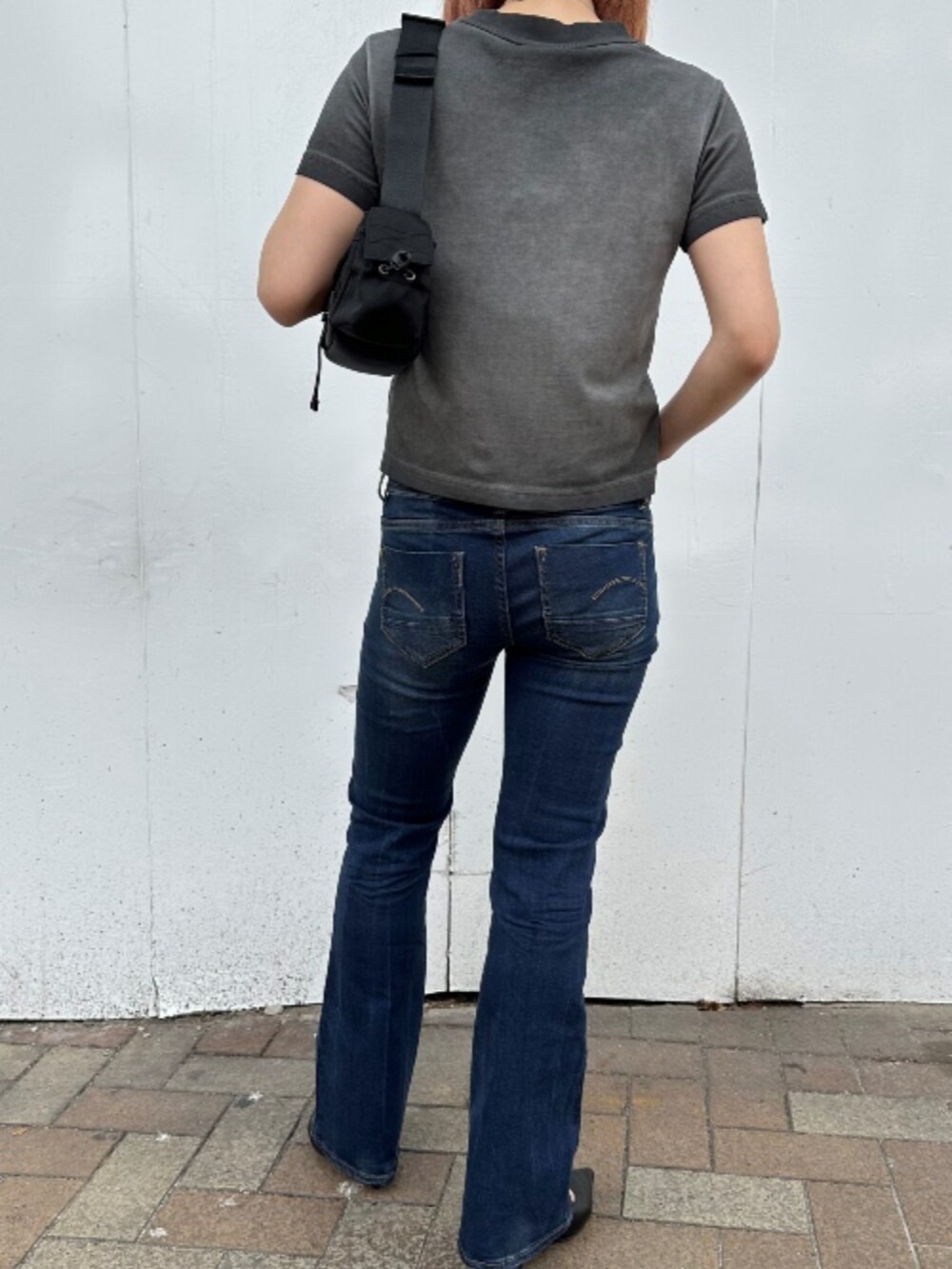 ブラック系のショルダーバッグ、ブラック系のTシャツ/カットソー、ブルー系のデニムパンツを着用したレディースの夏コーディネートの2枚目の写真