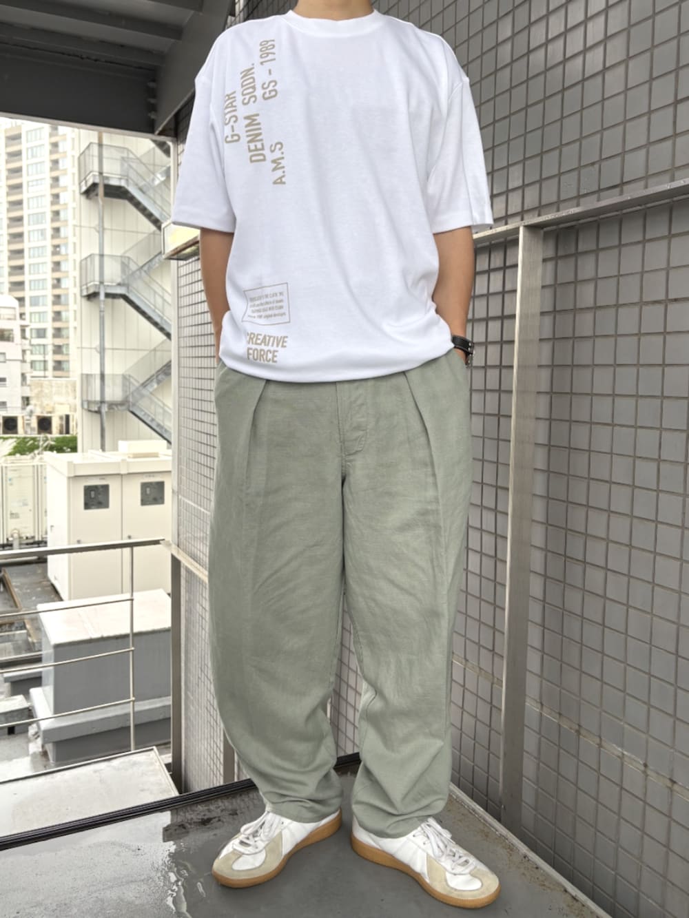 グリーン系のスラックス、ホワイト系のTシャツ/カットソーを着用したメンズの夏コーディネートの2枚目の写真