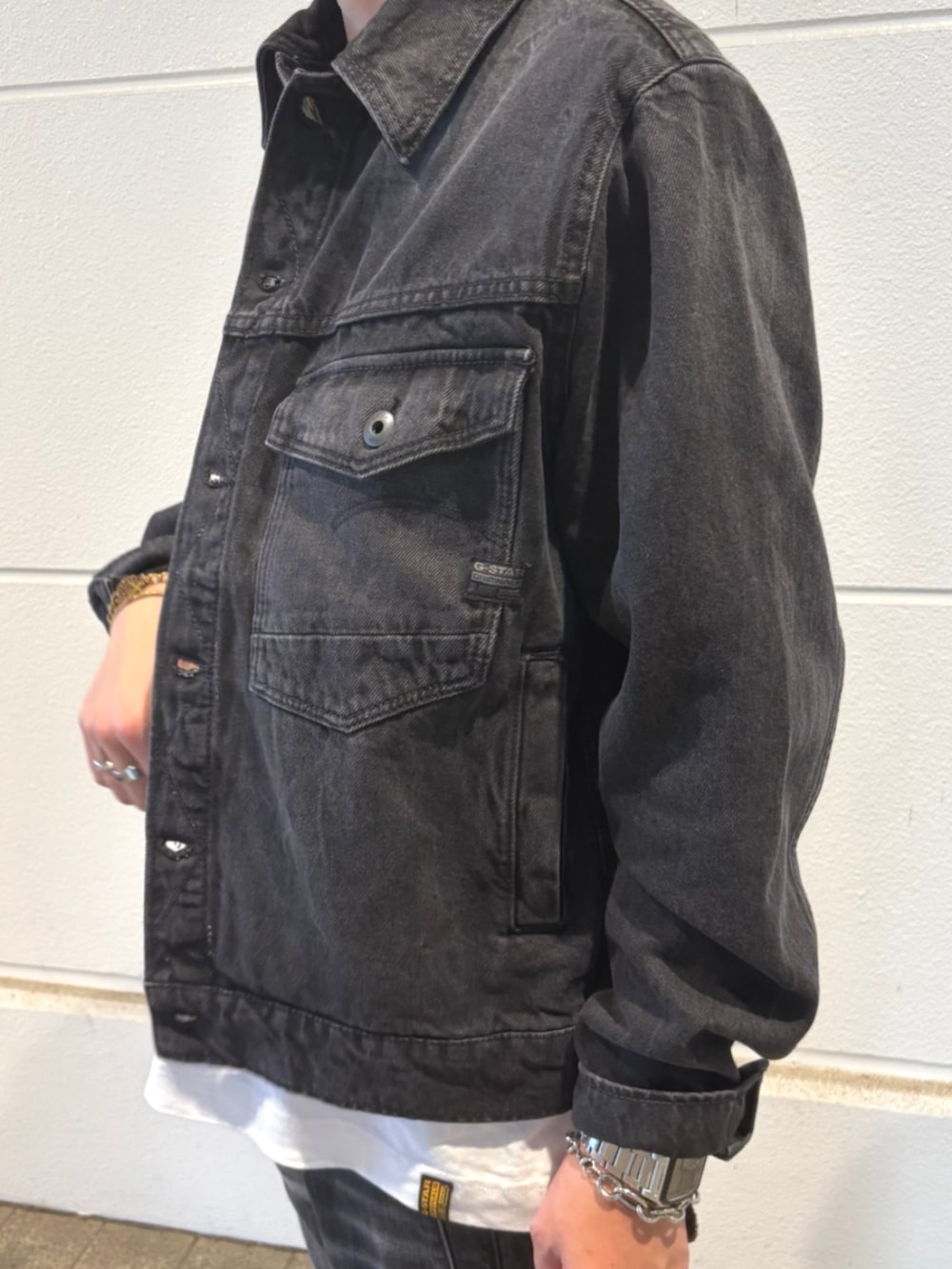 ホワイト系のTシャツ/カットソー、ブラック系のスニーカー、ブラック系のデニムジャケットを着用したメンズの夏コーディネートの2枚目の写真