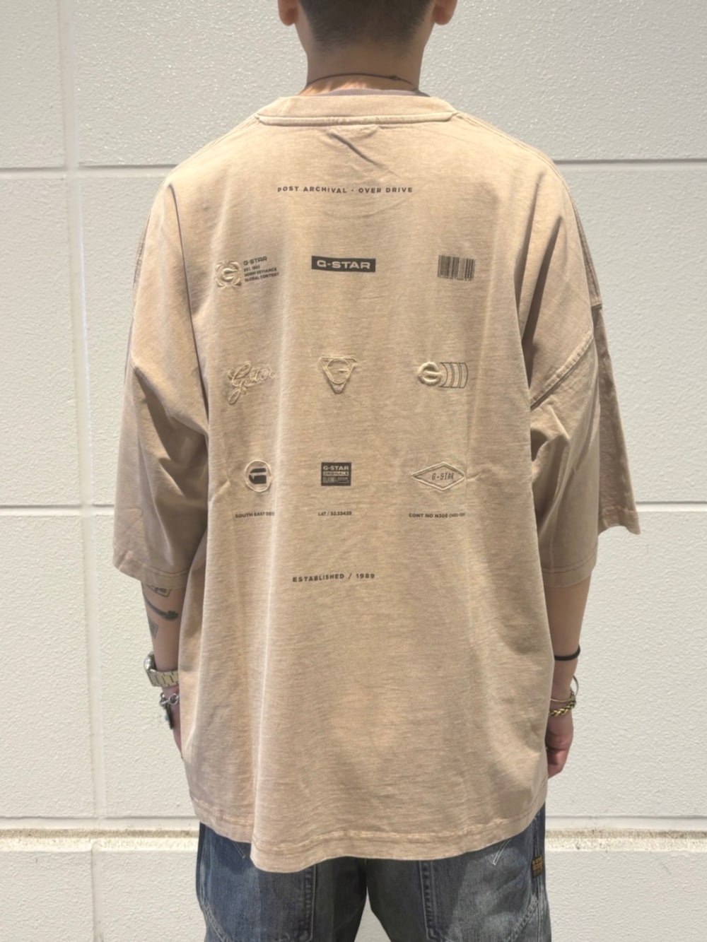 ベージュ系のTシャツ/カットソー、ブルー系のデニムパンツを着用したメンズの秋コーディネートの3枚目の写真