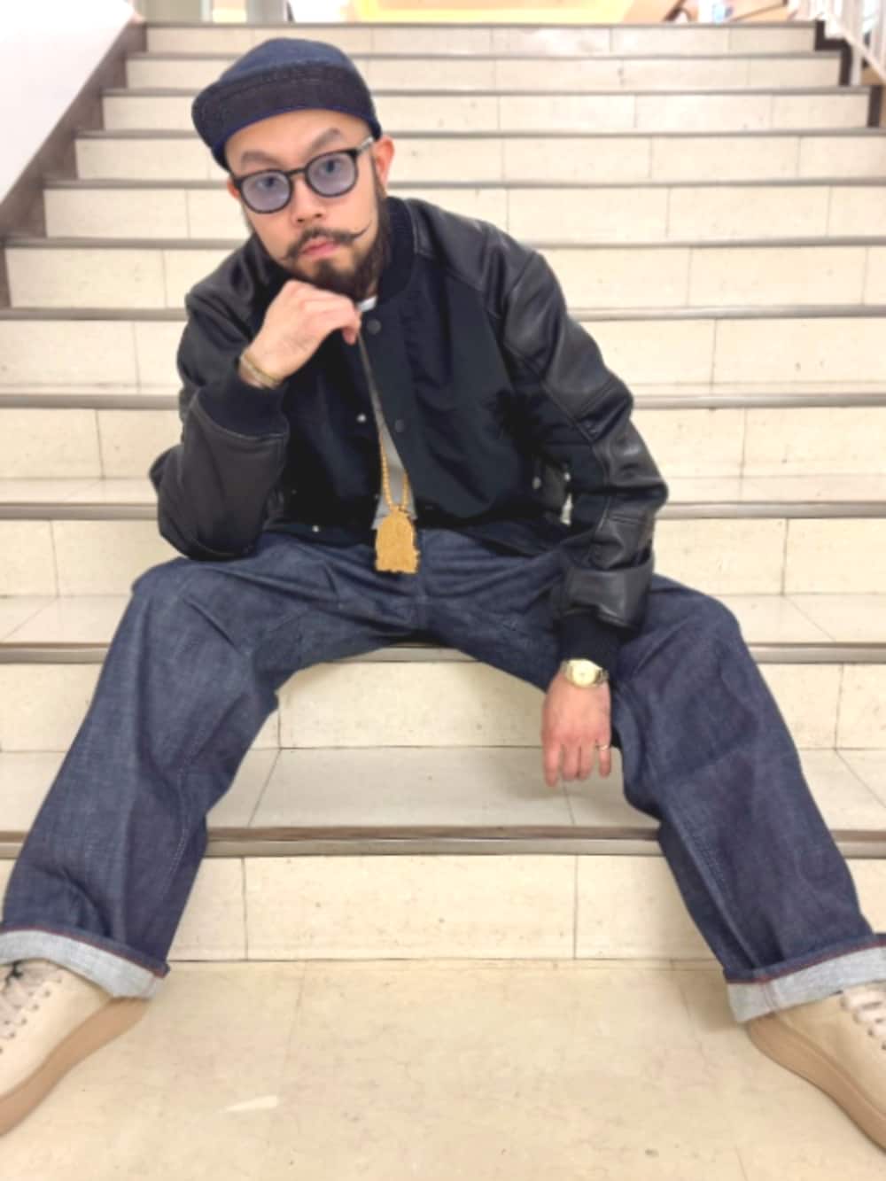 ブラック系のスタジャン、ブルー系のデニムパンツ、ブルー系のキャップを着用したメンズの秋コーディネートの3枚目の写真