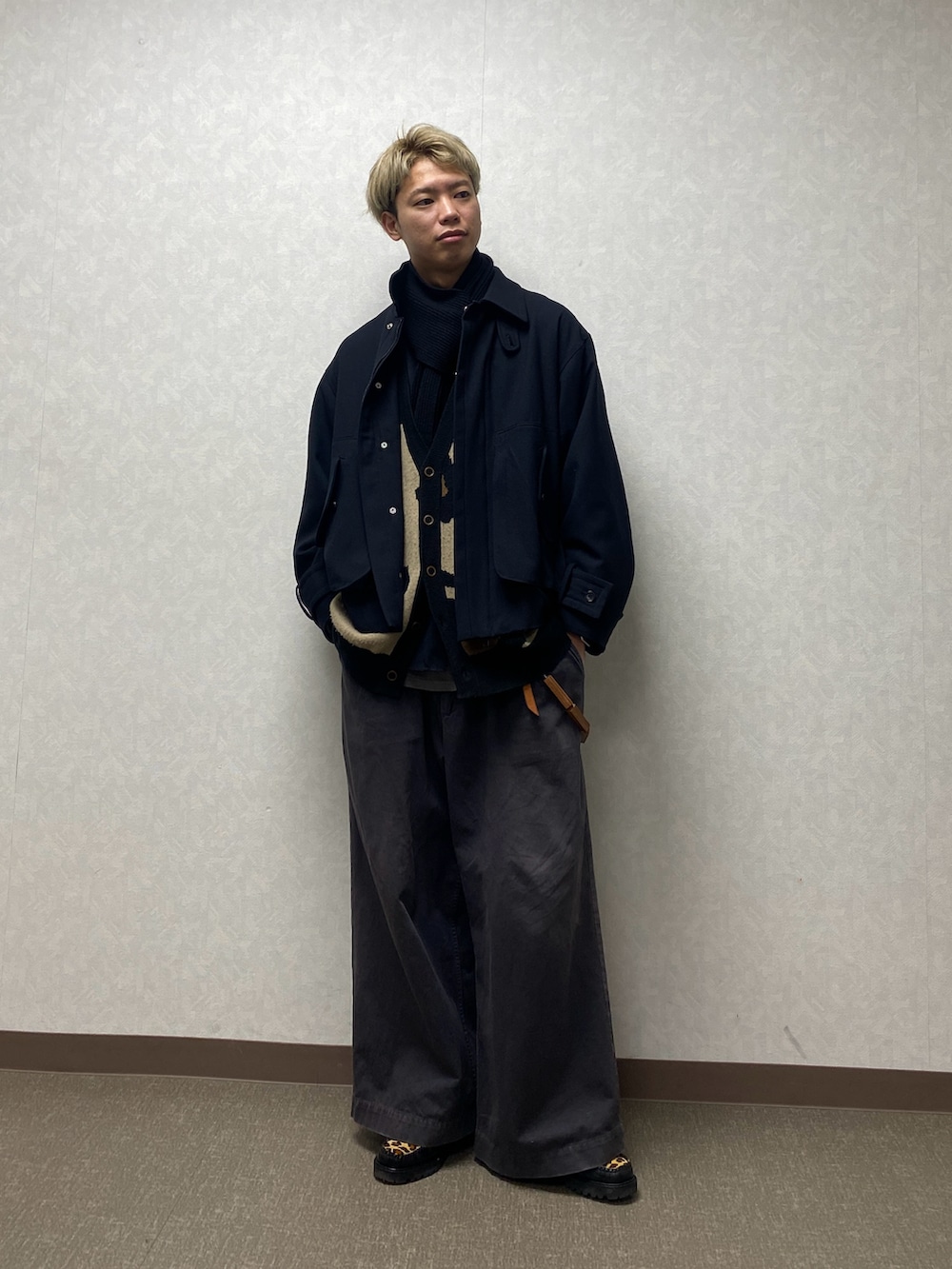 ブラック系のブルゾン、グレー系のチノパンツ、ベージュ系のカーディガン/ボレロを着用したメンズの冬コーディネートの2枚目の写真