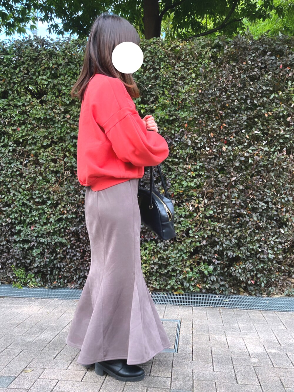 レッド系のスウェット、ブラウン系のスカート、ブラック系のバッグを着用したレディースの冬コーディネートの2枚目の写真