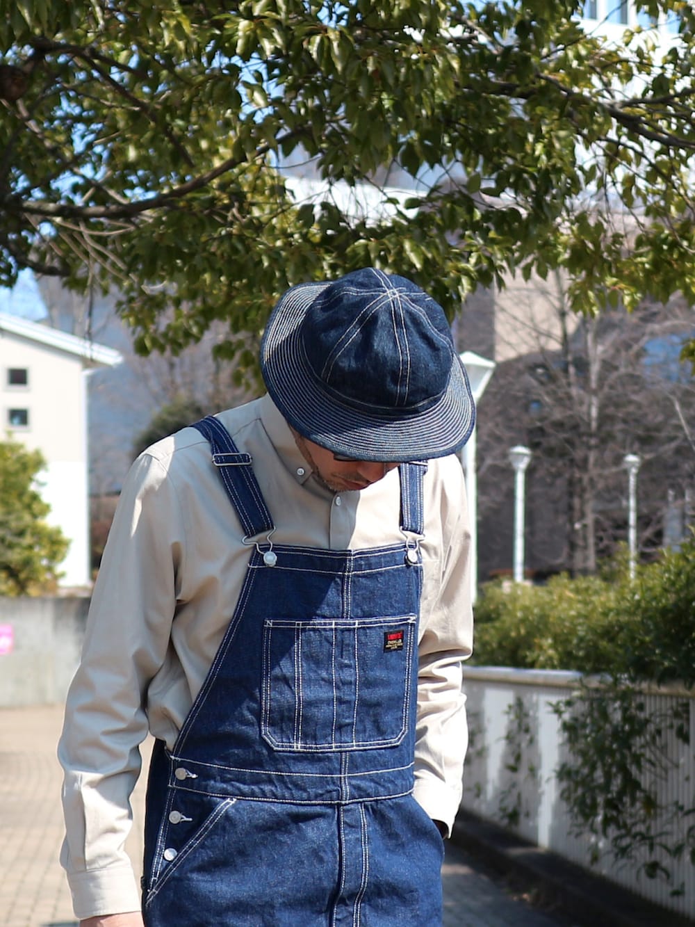 ブルー系のサロペット/オーバーオール、ブルー系のジャケット/アウター、ベージュ系のシャツ/ブラウスを着用したメンズの春コーディネートの2枚目の写真