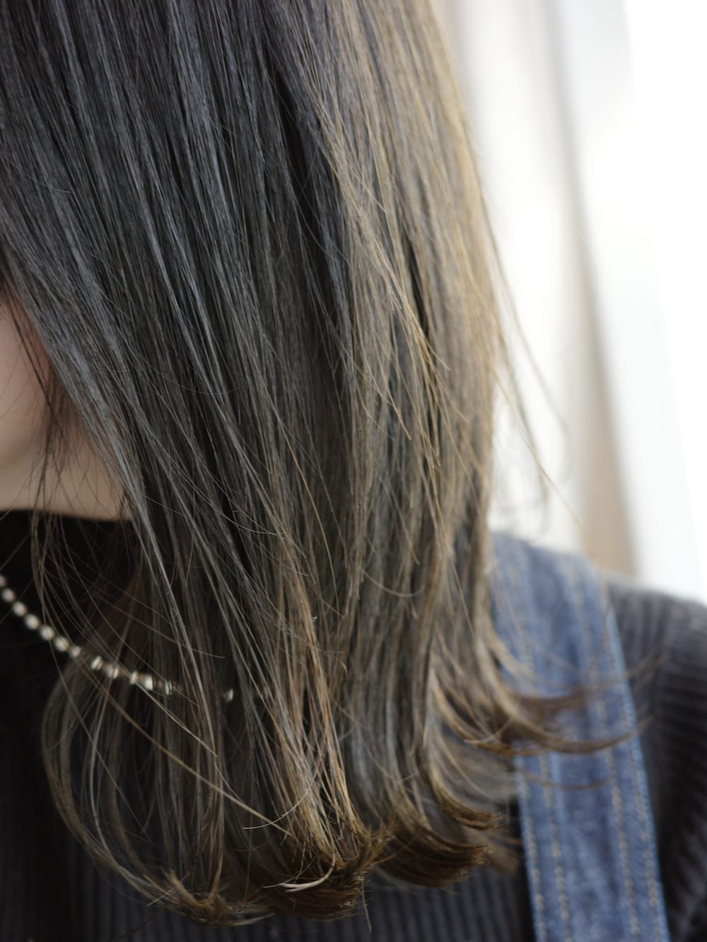 ブルー系のデニムスカート、ブラック系のニット/セーター、シルバー系のネックレスを着用したレディースの春コーディネートの2枚目の写真