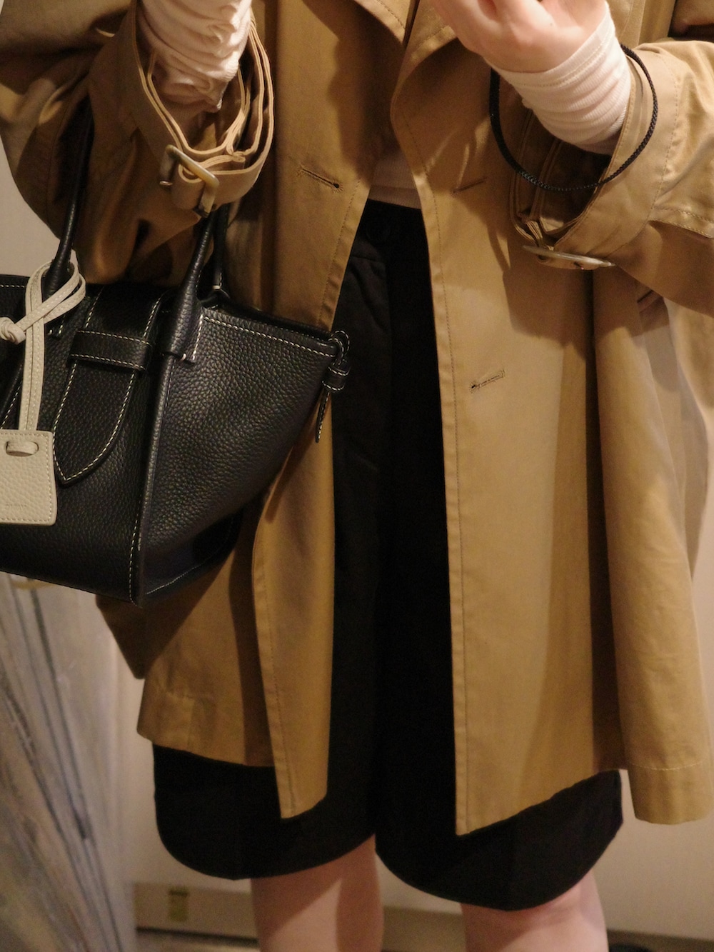 ブラック系のバッグ、ベージュ系のトレンチコート、ベージュ系のTシャツ/カットソーを着用したレディースの春コーディネートの2枚目の写真