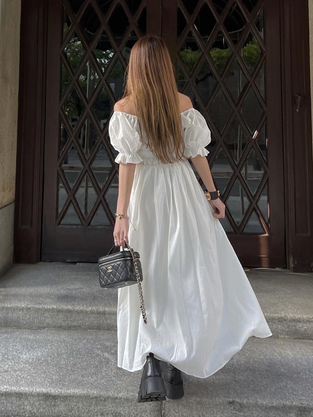 ホワイト系のワンピース、ブラック系のブーツ、ブラック系のショルダーバッグを着用したレディースの春コーディネートの5枚目の写真