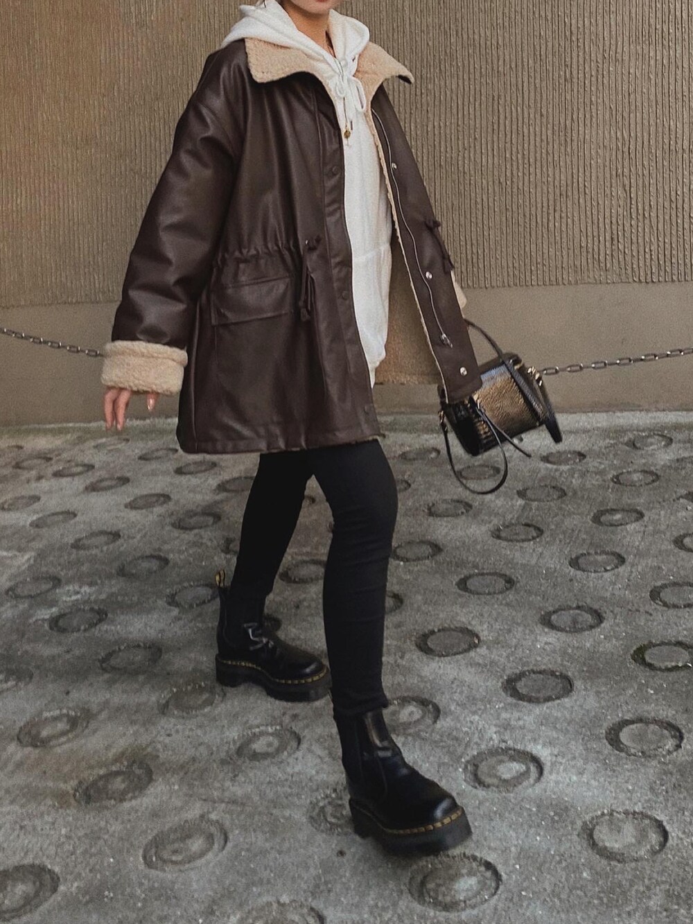 ブラウン系のジャケット/アウター、ホワイト系のパーカー、ブラック系のデニムパンツを着用したレディースの冬コーディネートの4枚目の写真