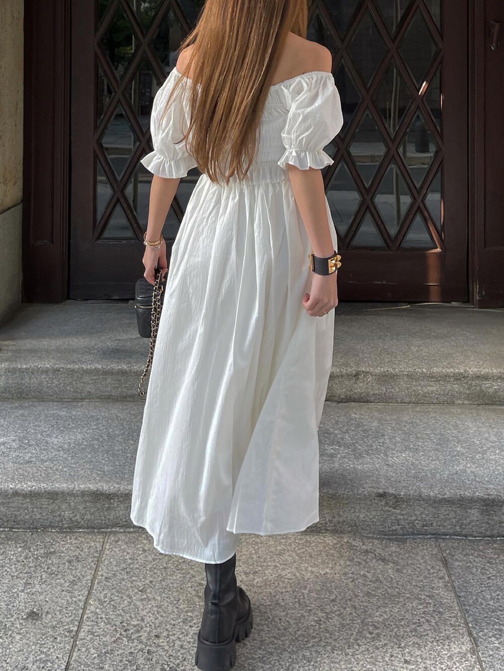 ホワイト系のワンピース、ブラック系のブーツ、ブラック系のショルダーバッグを着用したレディースの春コーディネートの4枚目の写真