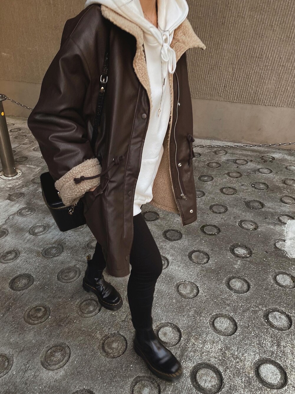 ブラウン系のジャケット/アウター、ホワイト系のパーカー、ブラック系のデニムパンツを着用したレディースの冬コーディネートの5枚目の写真