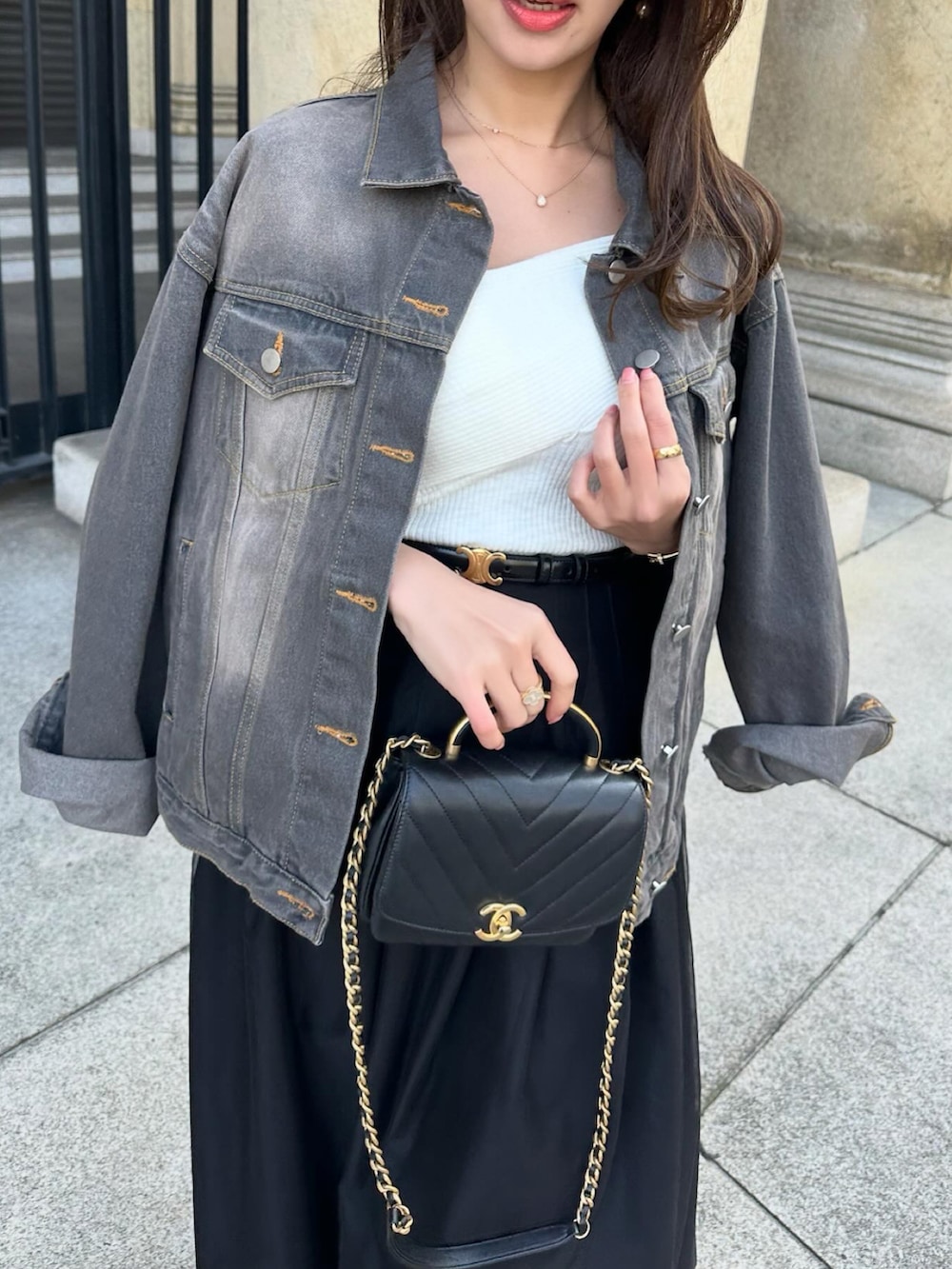 ブラック系のスカート、ブラック系のデニムジャケット、ブラック系のショルダーバッグを着用したレディースの春コーディネートの5枚目の写真