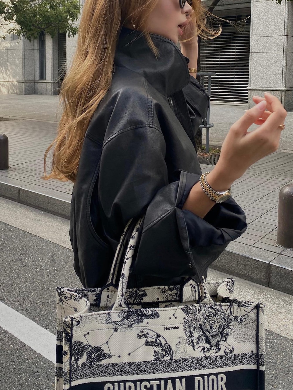 ホワイト系のトートバッグ、ブラック系のライダースジャケット、ブルー系のデニムパンツを着用したレディースの秋コーディネートの3枚目の写真