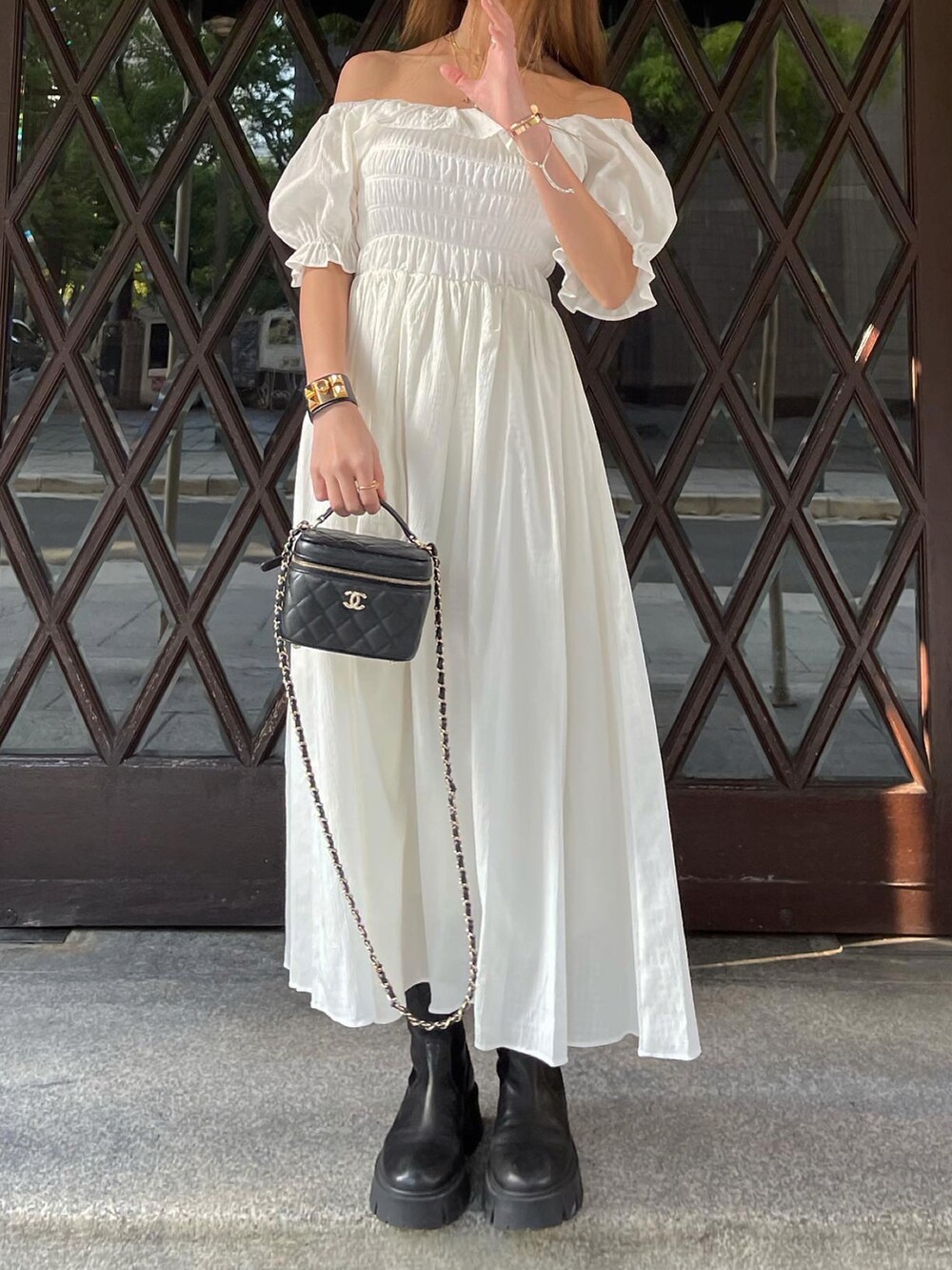 ホワイト系のワンピース、ブラック系のブーツ、ブラック系のショルダーバッグを着用したレディースの春コーディネートの2枚目の写真