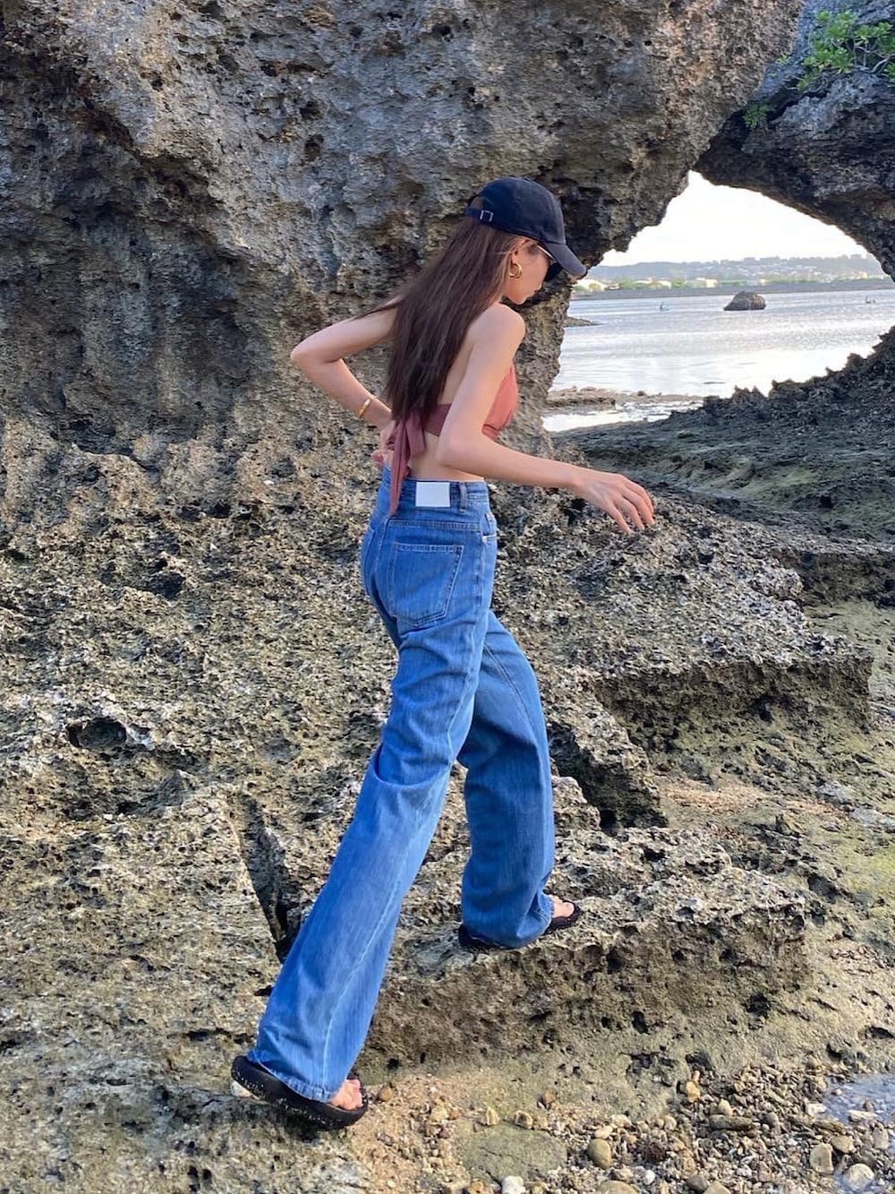 ブルー系のデニムパンツ、ピンク系の水着、ブラック系のキャップを着用したレディースの夏コーディネートの2枚目の写真