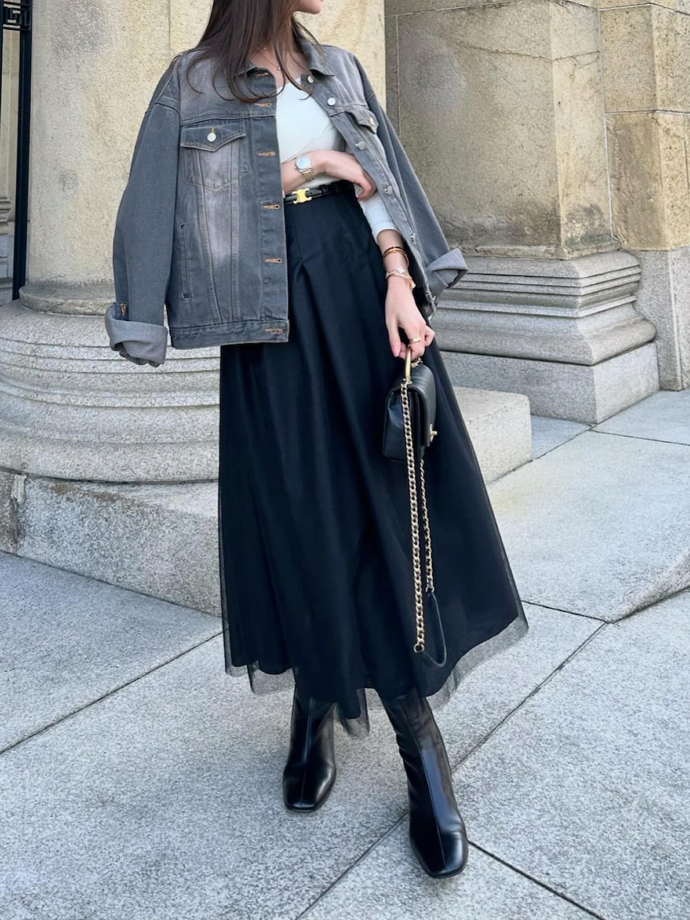 ブラック系のスカート、ブラック系のデニムジャケット、ブラック系のショルダーバッグを着用したレディースの春コーディネートの4枚目の写真