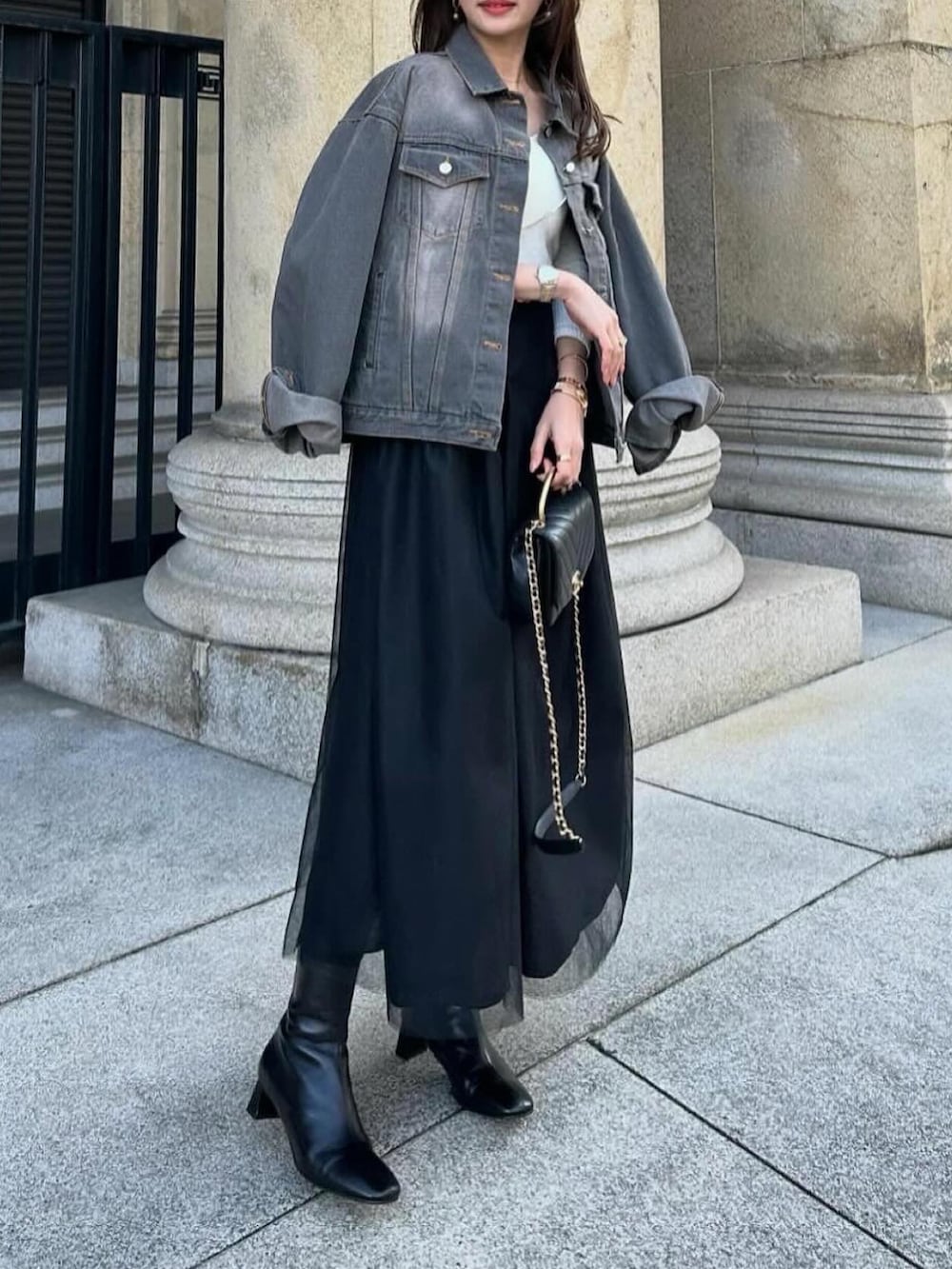 ブラック系のスカート、ブラック系のデニムジャケット、ブラック系のショルダーバッグを着用したレディースの春コーディネートの3枚目の写真