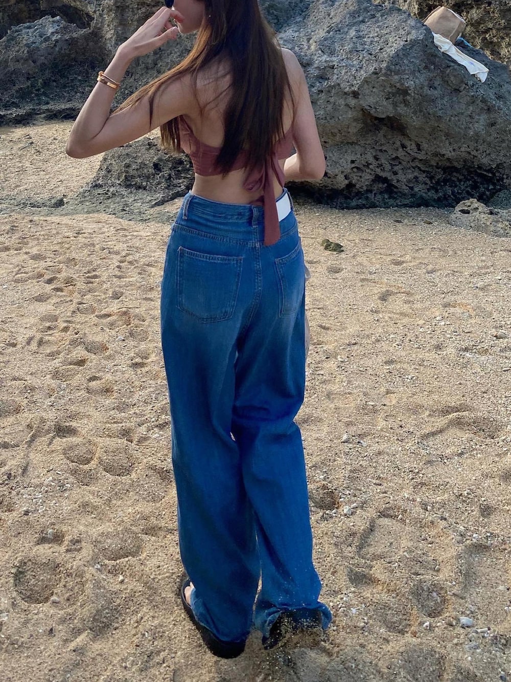 ブルー系のデニムパンツ、ピンク系の水着、ブラック系のキャップを着用したレディースの夏コーディネートの3枚目の写真