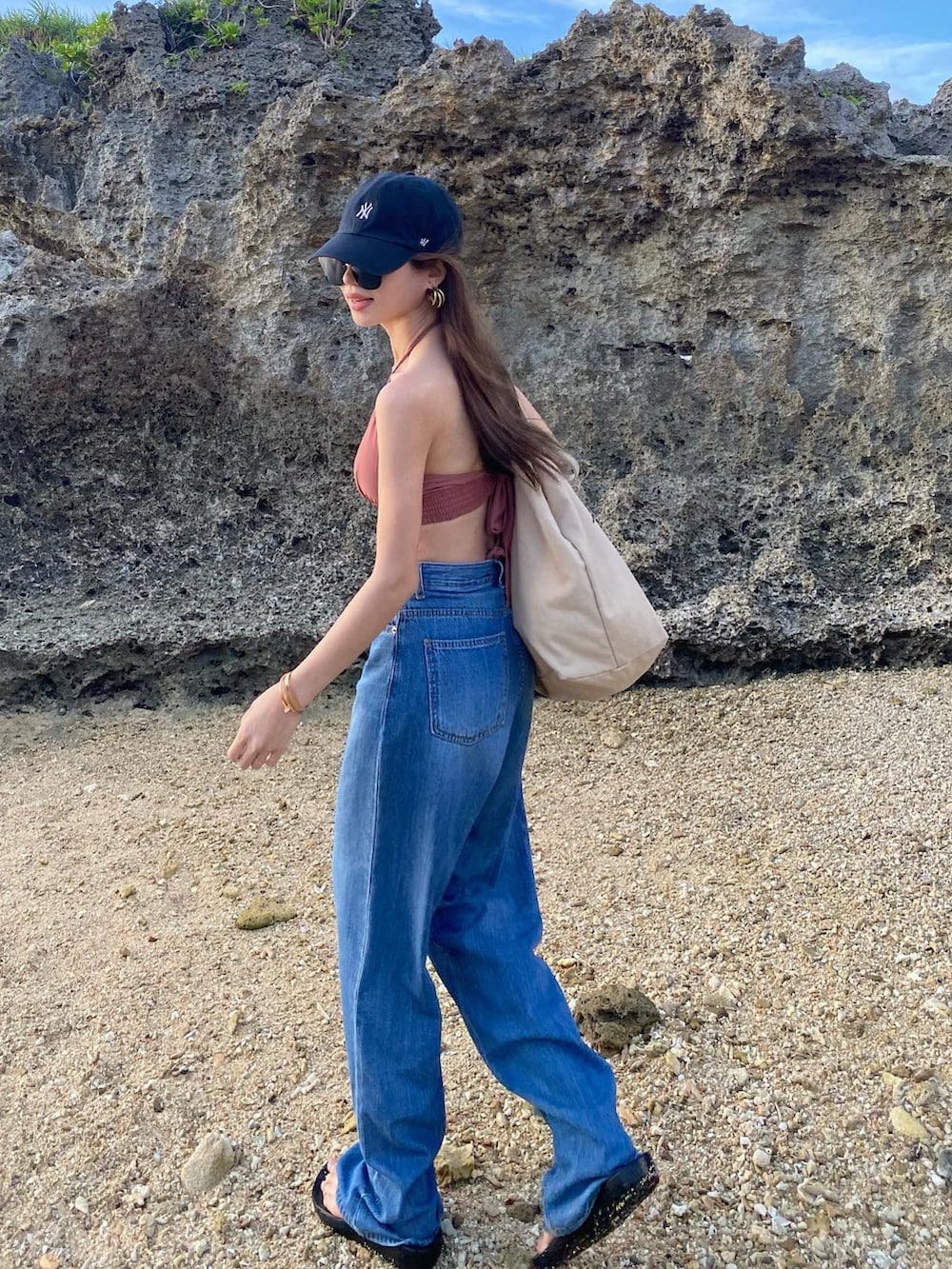 ブルー系のデニムパンツ、ピンク系の水着、ブラック系のキャップを着用したレディースの夏コーディネートの5枚目の写真