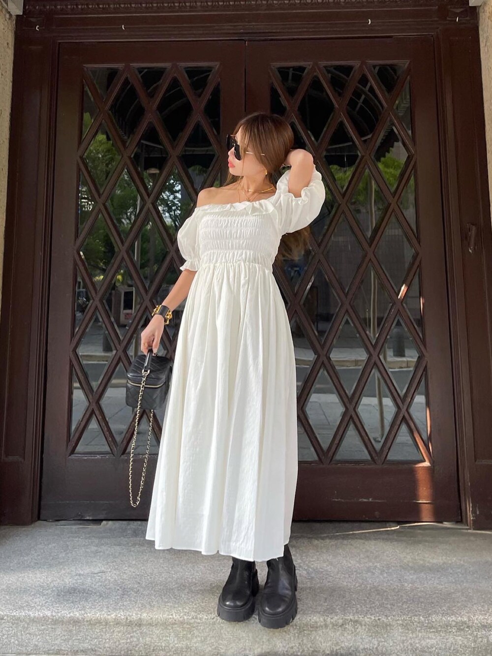 ホワイト系のワンピース、ブラック系のブーツ、ブラック系のショルダーバッグを着用したレディースの春コーディネートの3枚目の写真