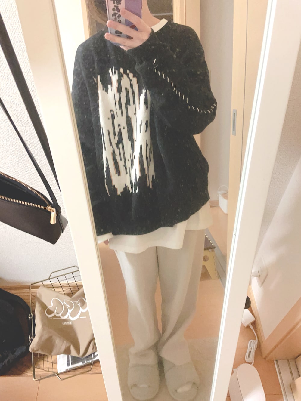 ホワイト系のブルゾン、ホワイト系のTシャツ/カットソー、ブラック系のニット/セーターを着用したレディースの冬コーディネートの2枚目の写真