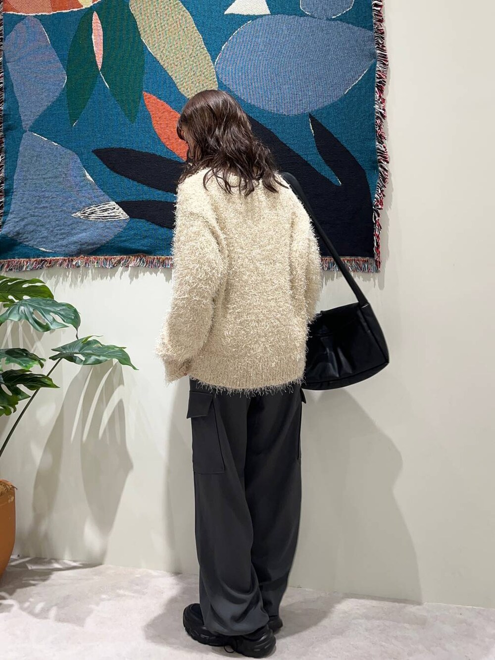 ブラック系のショルダーバッグ、ホワイト系のカーディガン/ボレロ、ブラック系のスニーカーを着用したレディースの秋コーディネートの2枚目の写真