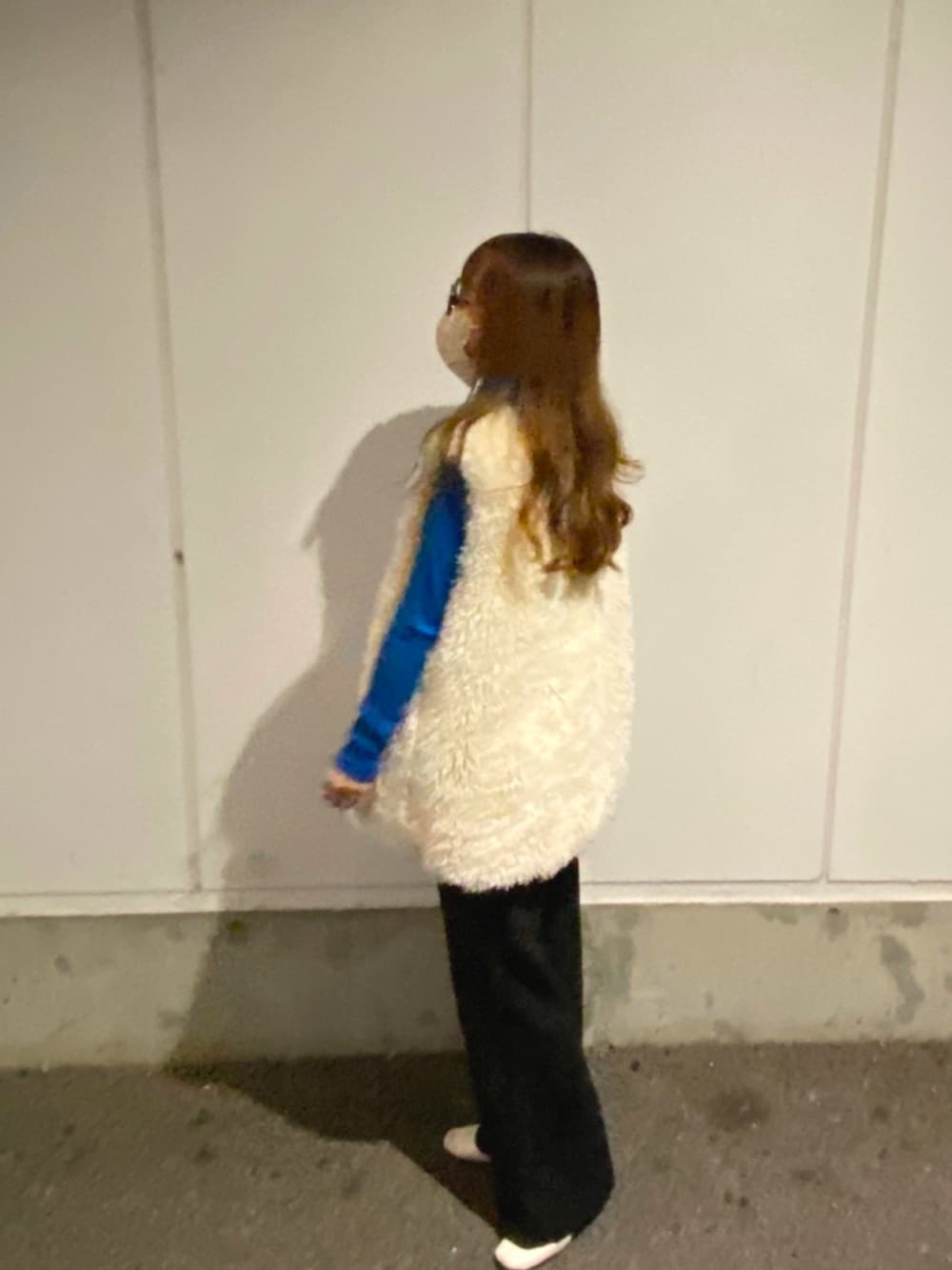 ブルー系のニット/セーター、ホワイト系のベスト、ブラック系のスラックスを着用したレディースの秋コーディネートの2枚目の写真