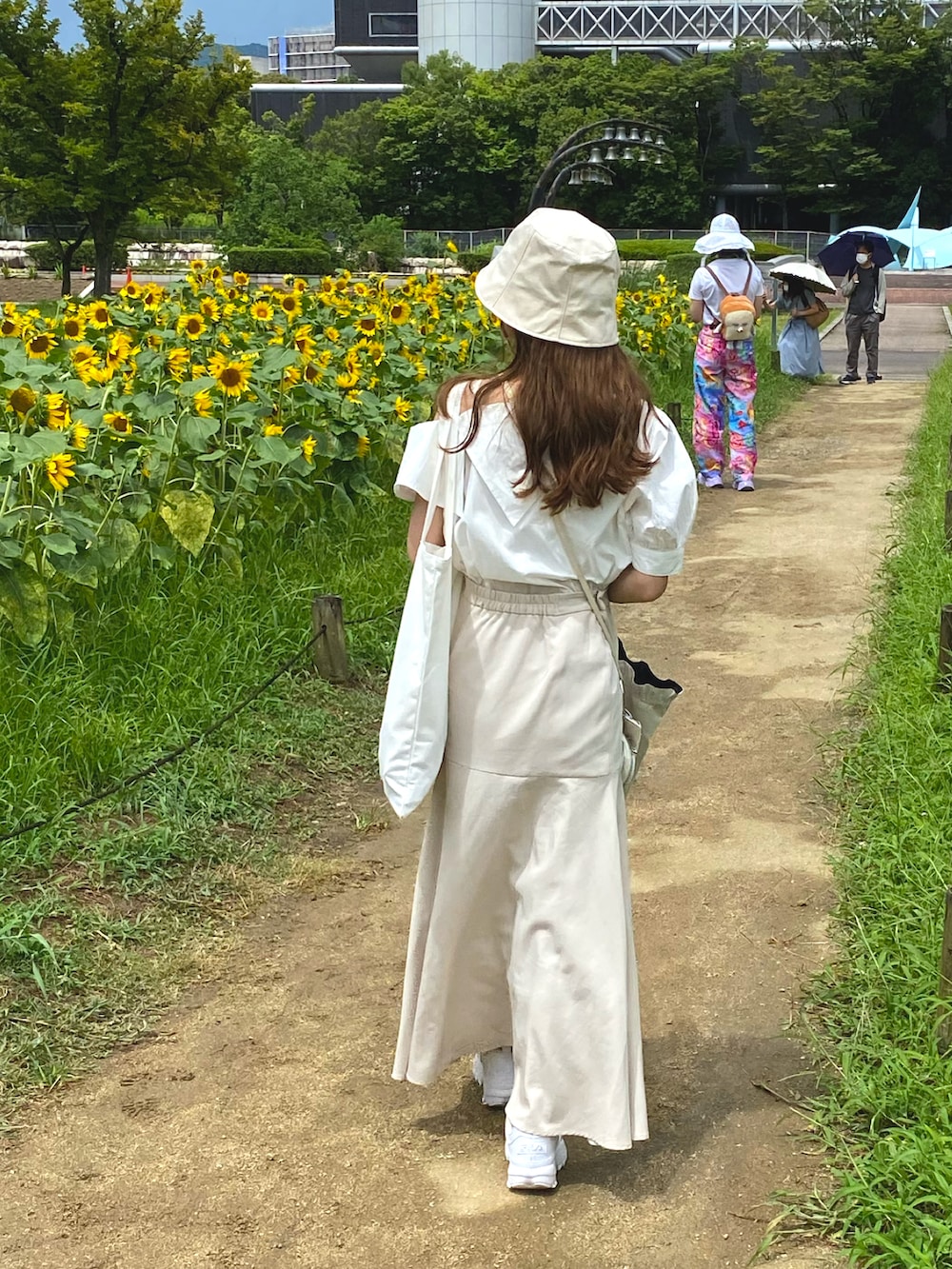 ホワイト系のシャツ/ブラウス、ホワイト系のスカート、ホワイト系のトートバッグを着用したレディースの夏コーディネートの2枚目の写真