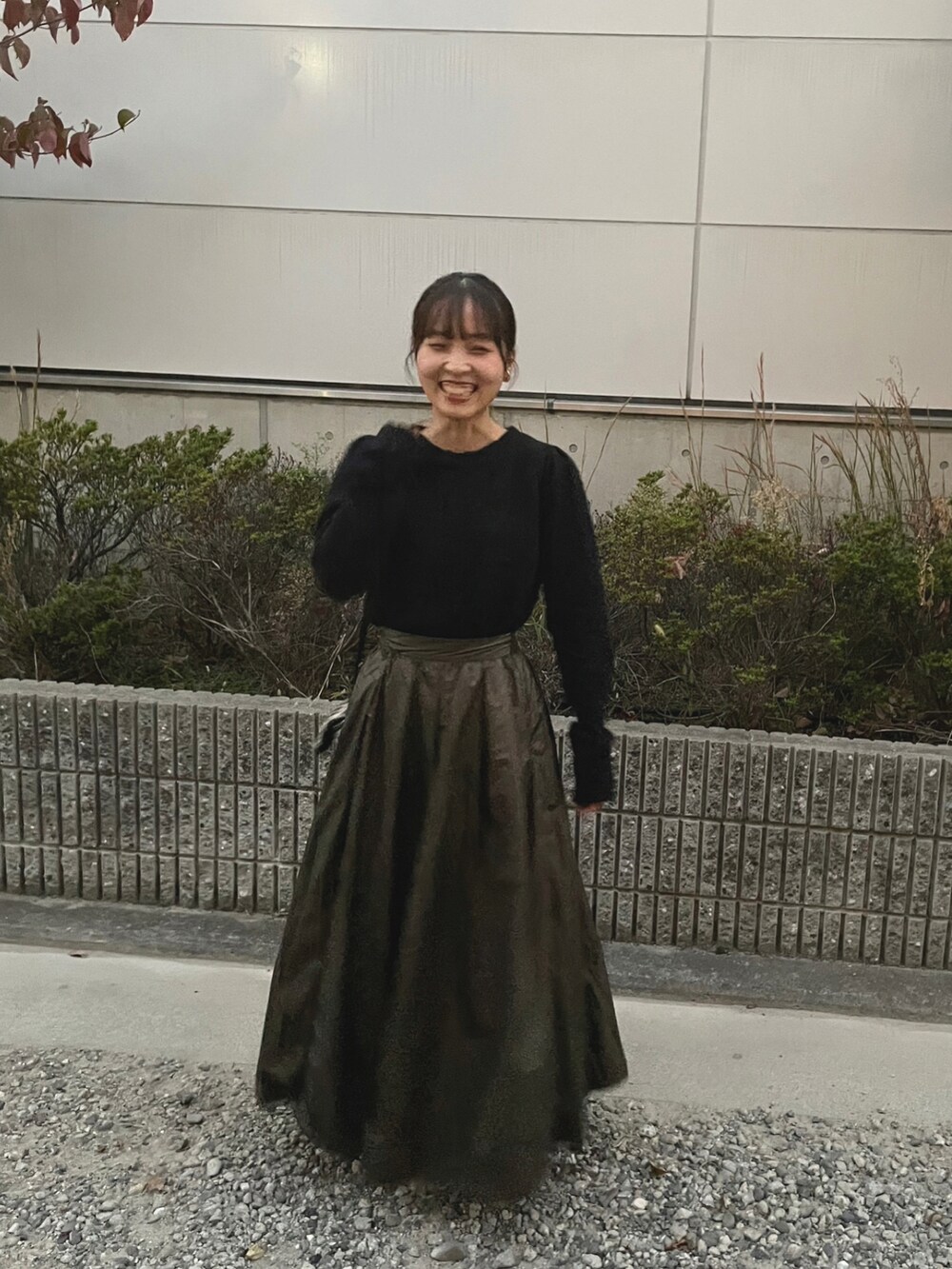 ブラック系のニット/セーター、グリーン系のスカート、ブラック系のバッグを着用したレディースの秋コーディネートの2枚目の写真