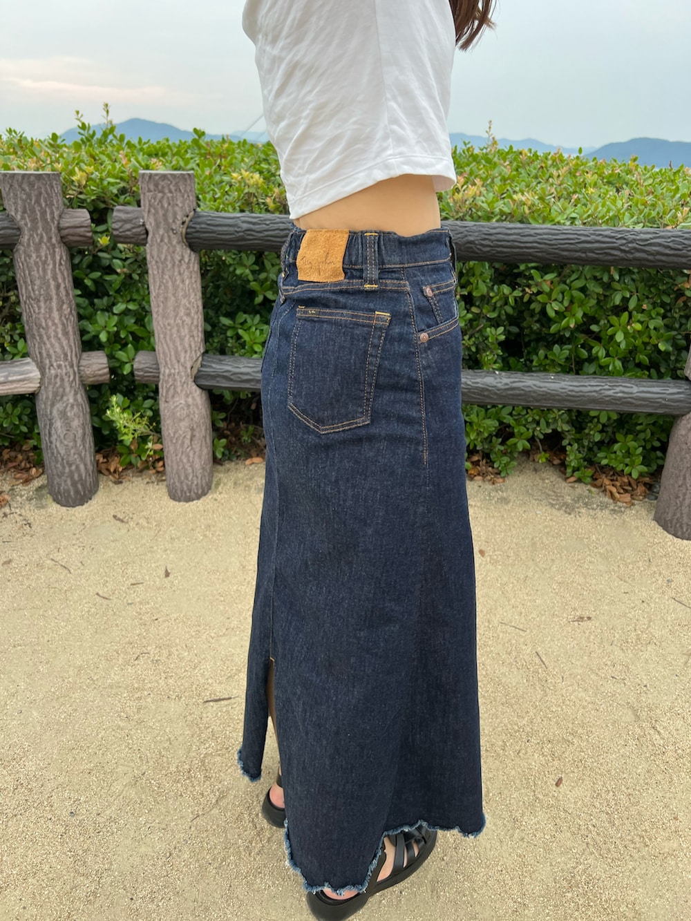 ホワイト系のTシャツ/カットソー、ブルー系のデニムスカート、ブラック系のショルダーバッグを着用したレディースの夏コーディネートの2枚目の写真