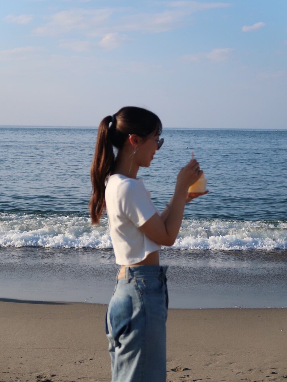 ブルー系のバッグ、ホワイト系のTシャツ/カットソー、ブルー系のデニムパンツを着用したレディースの夏コーディネートの2枚目の写真