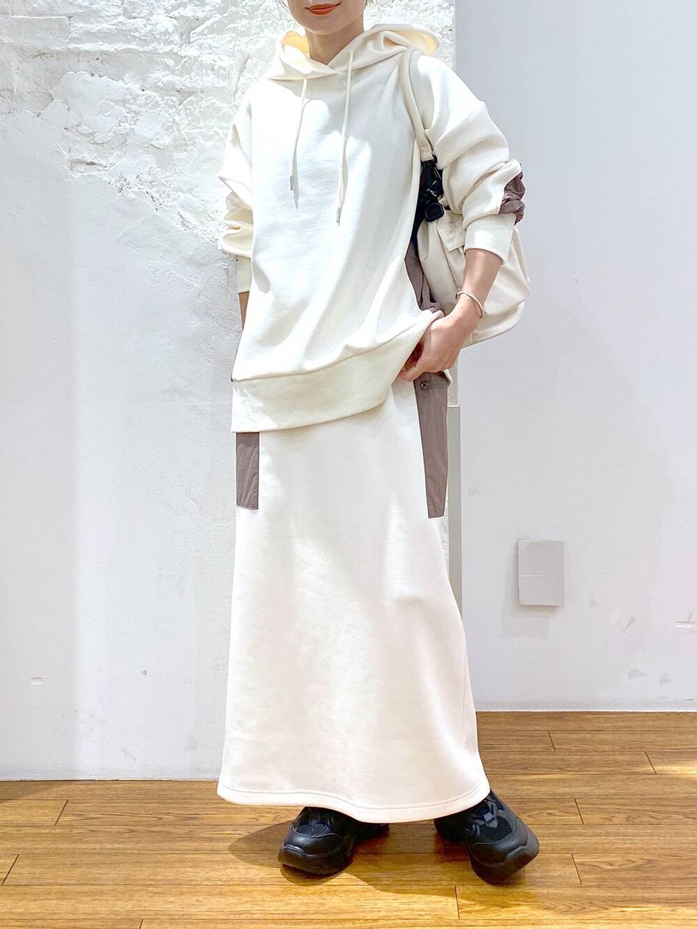 ホワイト系のショルダーバッグ、ブラック系のスニーカー、ホワイト系のパーカーを着用したレディースの秋コーディネートの2枚目の写真